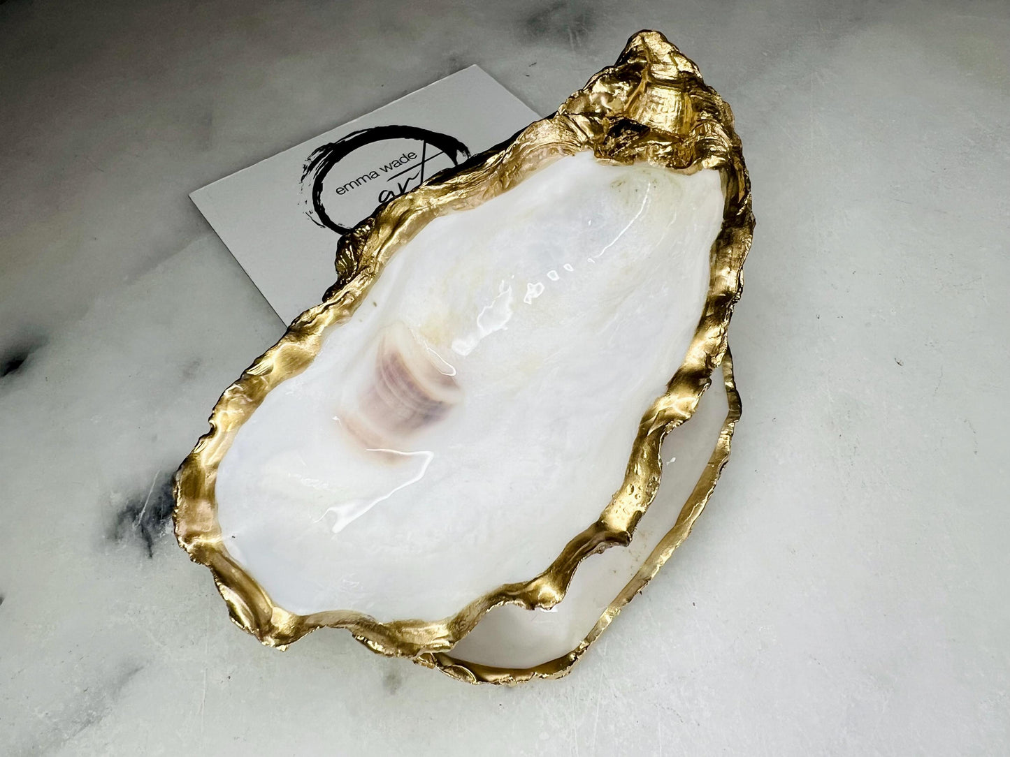 Extra large Dorset oyster shell serving dish set with natural pearl interior and hand-applied gold leaf edging, featuring a cupped XL oyster shell with matching flat shell base. Luxury coastal home décor ideal as a sugar dish, serving bowl, coffee station accessory, or elegant host gift. Handmade using sustainably sourced UK oyster shells and finished with glossy resin and optional gold serving accessories.