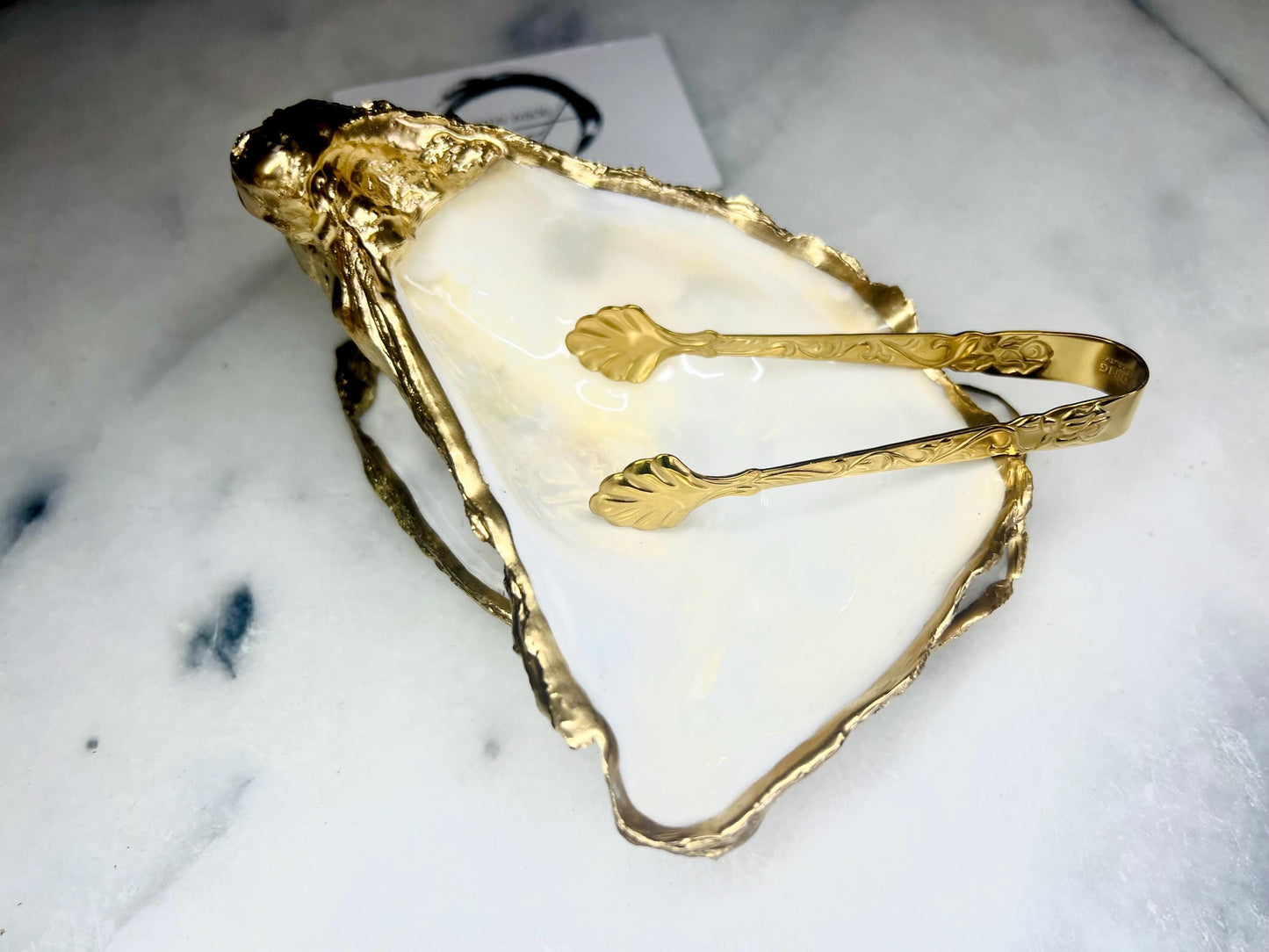 Extra large Dorset oyster shell serving dish set with natural pearl interior and hand-applied gold leaf edging, featuring a cupped XL oyster shell with matching flat shell base. Luxury coastal home décor ideal as a sugar dish, serving bowl, coffee station accessory, or elegant host gift. Handmade using sustainably sourced UK oyster shells and finished with glossy resin and optional gold serving accessories.