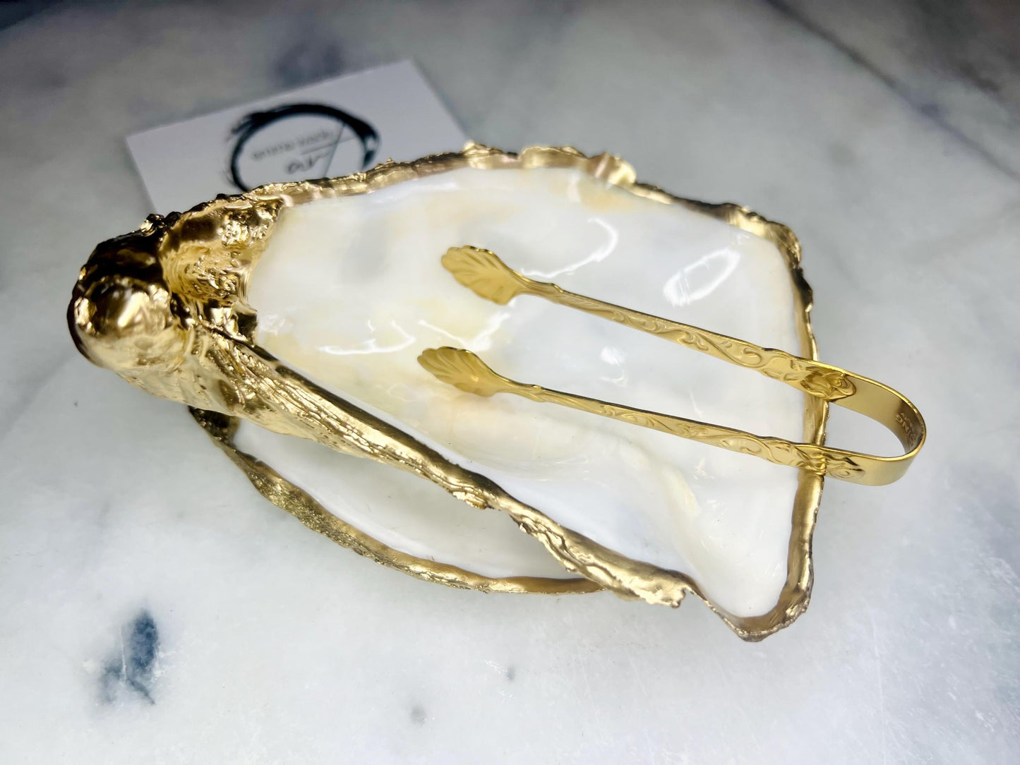Extra large Dorset oyster shell serving dish set with natural pearl interior and hand-applied gold leaf edging, featuring a cupped XL oyster shell with matching flat shell base. Luxury coastal home décor ideal as a sugar dish, serving bowl, coffee station accessory, or elegant host gift. Handmade using sustainably sourced UK oyster shells and finished with glossy resin and optional gold serving accessories.