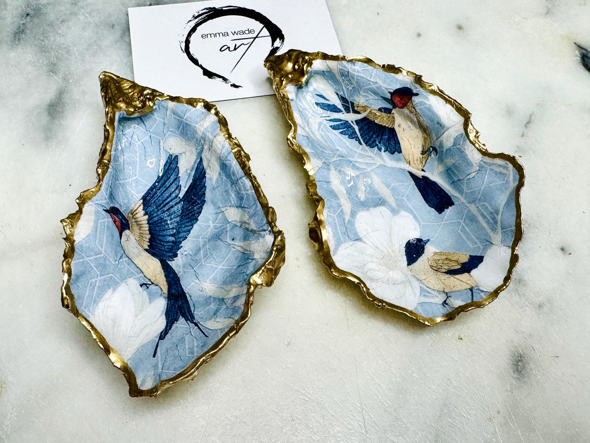 Handmade blue bird oyster shell salt and pepper dishes shown as a matching pair without spoons, featuring a delicate bird design and hand-gilded gold leaf edges. Crafted from natural Dorset oyster shells and sealed with a glossy finish, these coastal-inspired pinch pots are perfect for elegant table decor, weddings, or a unique hostess gift. Each shell is one of a kind and finished by hand.