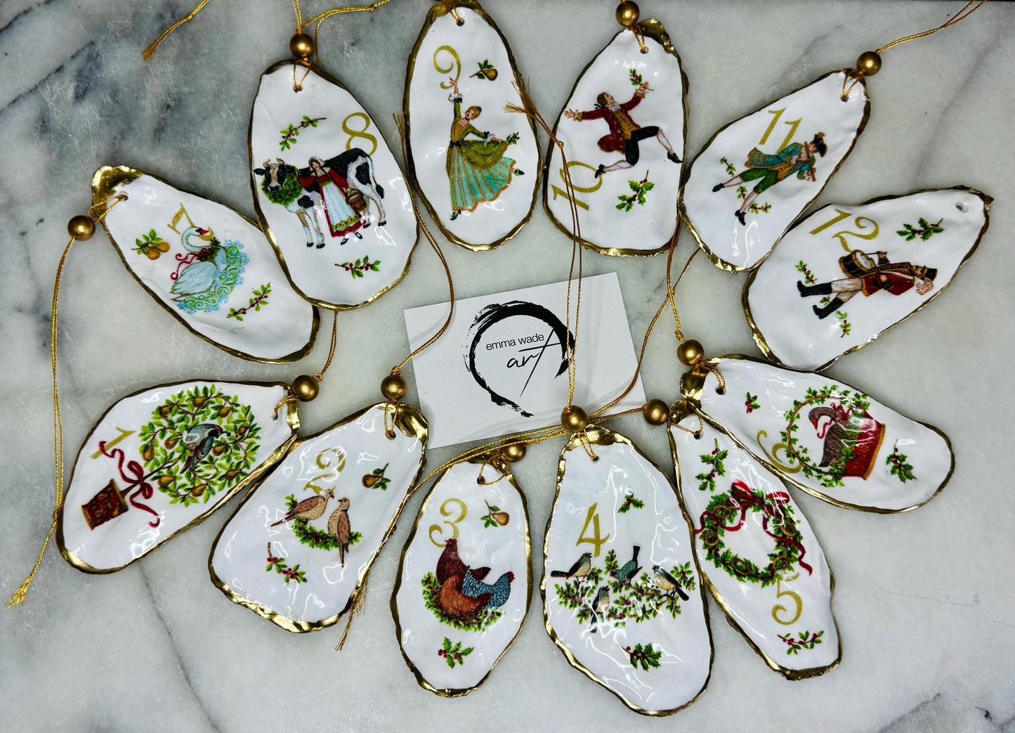 Handmade Twelve Days of Christmas oyster shell ornament set featuring all twelve traditional carol illustrations, finished with gold leaf edging, glossy resin and gold hanging cords. Coastal heirloom Christmas decorations handcrafted from Dorset oyster shells.