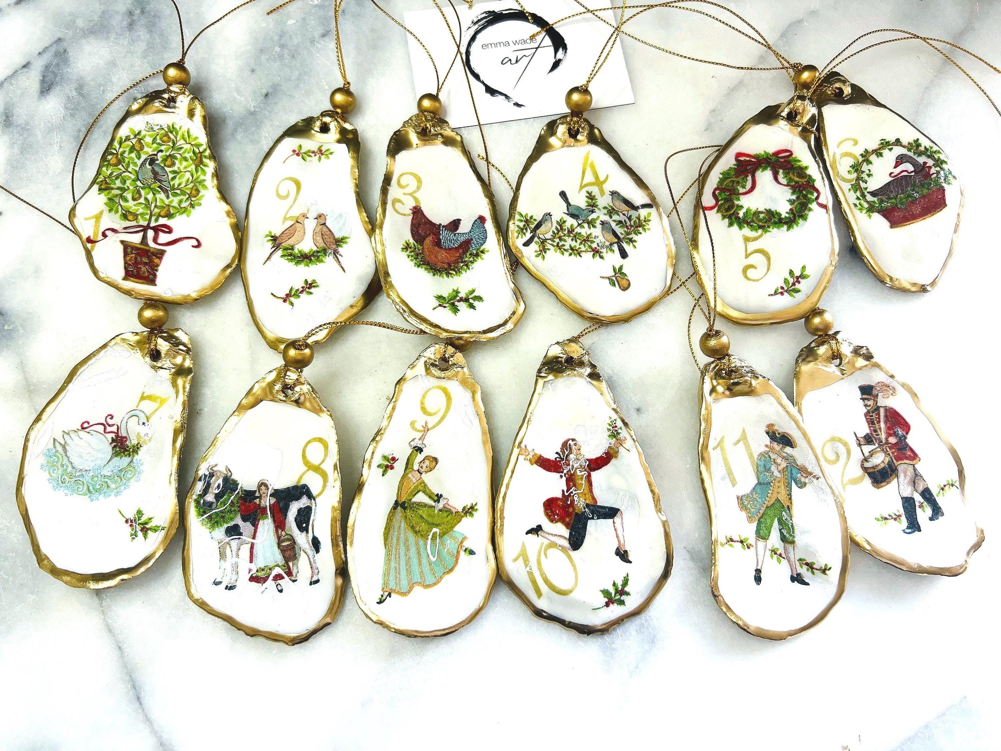Handmade Twelve Days of Christmas oyster shell ornament set featuring all twelve traditional carol illustrations, finished with gold leaf edging, glossy resin and gold hanging cords. Coastal heirloom Christmas decorations handcrafted from Dorset oyster shells.