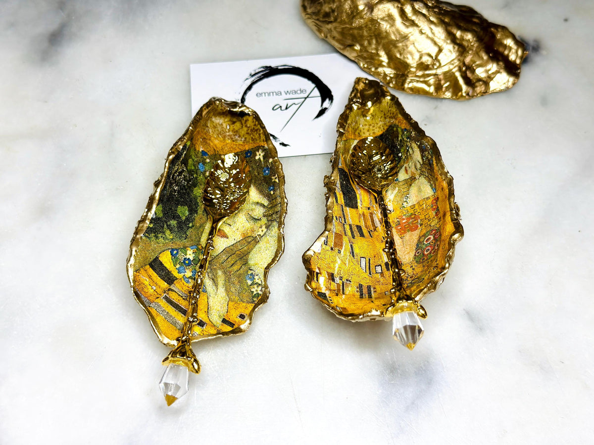 Pair of handmade Dorset oyster shell salt and pepper pinch pots inspired by Gustav Klimt’s The Kiss, decorated with rich gold artwork, hand-finished with liquid gold leaf, and sealed in crystal-hard glossy resin. Luxury coastal serving dishes with optional gold crystal spoons, perfect for weddings, anniversaries, dinner parties, and elegant table décor.