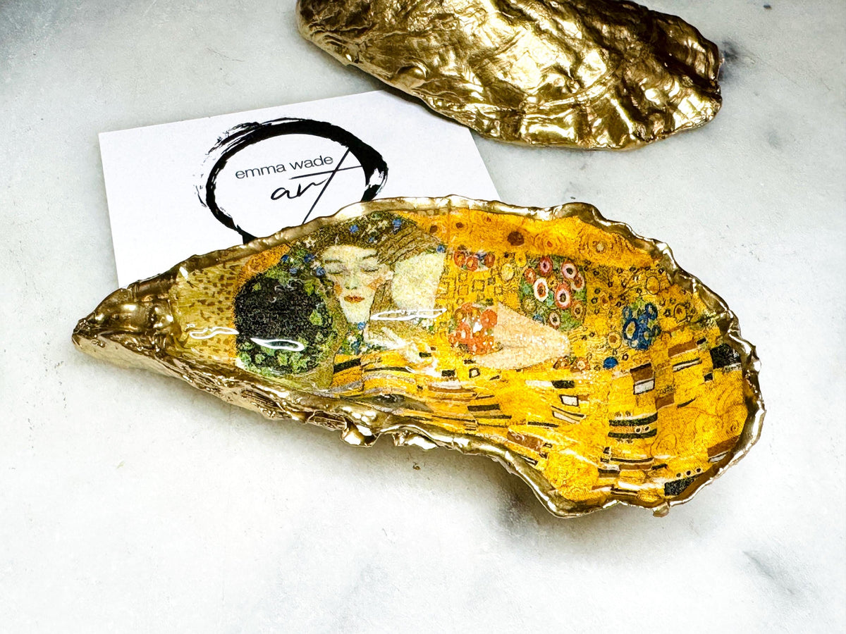 Pair of handmade Dorset oyster shell salt and pepper pinch pots inspired by Gustav Klimt’s The Kiss, decorated with rich gold artwork, hand-finished with liquid gold leaf, and sealed in crystal-hard glossy resin. Luxury coastal serving dishes with optional gold crystal spoons, perfect for weddings, anniversaries, dinner parties, and elegant table décor.