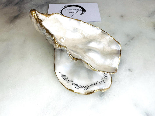 Handmade Dorset oyster shell jewellery dish set with a cupped oyster shell resting on a flat shell base, finished with natural pearl interiors and gold leaf edging. Personalised coastal trinket dish handcrafted in the UK, ideal for holding rings or jewellery. Elegant shell decor presented in sustainable gift packaging, perfect for weddings, anniversaries or special occasions.