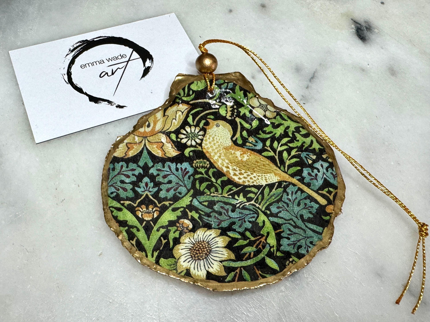 Handmade William Morris Strawberry Thief scallop shell hanging ornaments in four colourways with birds, floral patterns and gold leaf edging. Coastal shell ornaments finished in glossy resin with gold hanging cords for Christmas trees or year-round home decor. UK Heritage Gift