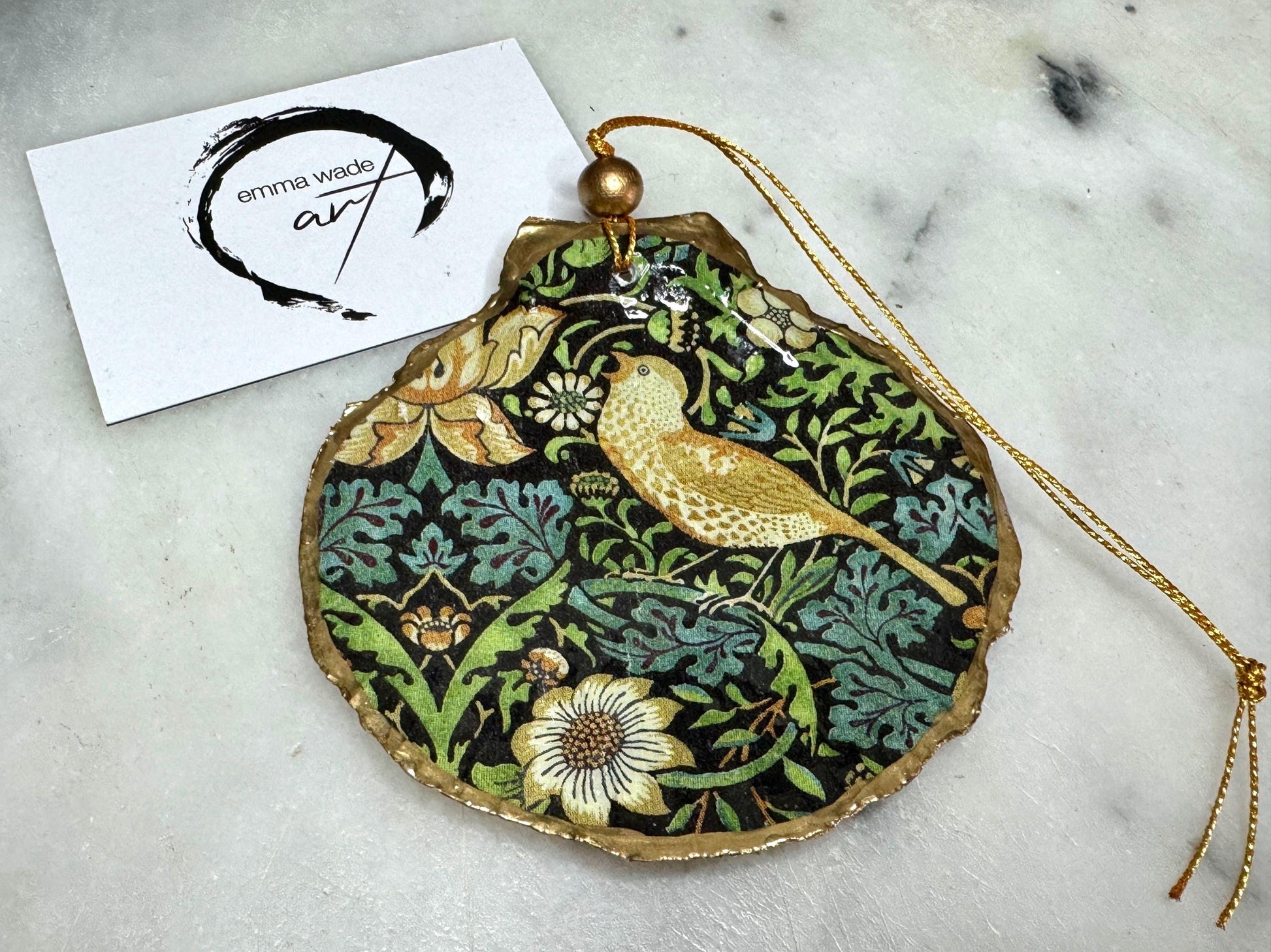 Handmade William Morris Strawberry Thief scallop shell hanging ornaments in four colourways with birds, floral patterns and gold leaf edging. Coastal shell ornaments finished in glossy resin with gold hanging cords for Christmas trees or year-round home decor. UK Heritage Gift