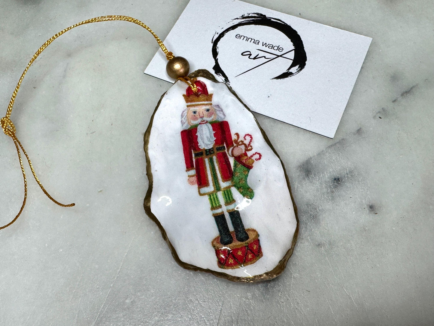 Handmade Nutcracker oyster shell Christmas ornaments with gold gilded edges and glossy resin finish. Traditional festive Nutcracker designs on natural pearl Dorset oyster shells in red, green, aqua, blue and gold tones, styled as luxury coastal Christmas tree decorations.