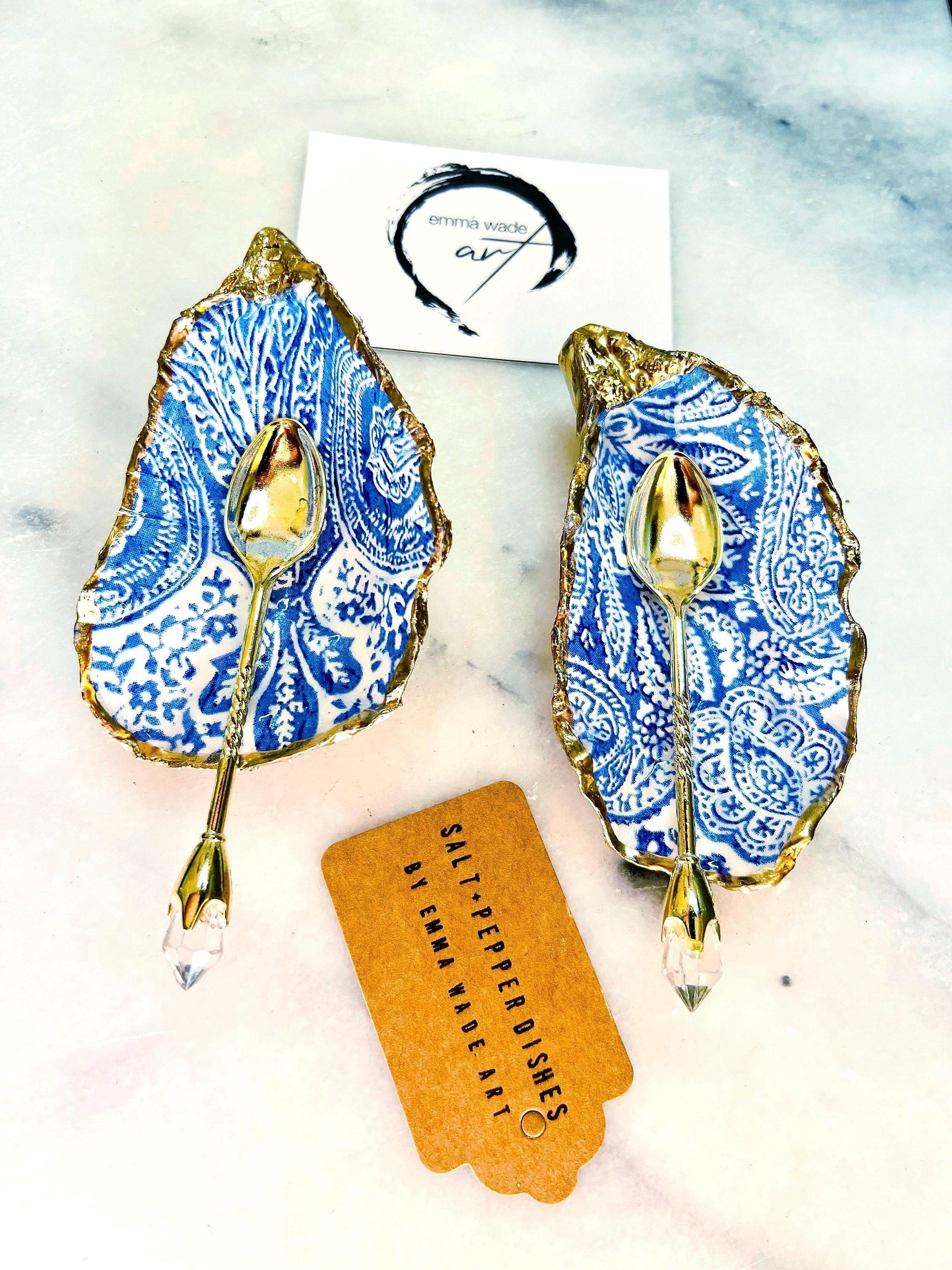 Blue and white paisley oyster shell salt cellar set with gold leaf edging and matching gold crystal spoons. Handmade Dorset oyster shell pinch pots finished in glossy food safe resin. Coastal dining decor and luxury beach house table accessory.
