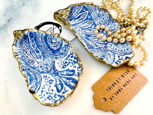 Handmade Dorset oyster shell trinket dish featuring an elegant blue and white paisley design, hand-gilded with liquid gold leaf and finished in glossy resin. Coastal shell jewellery holder available in multiple sizes from small to XL, ideal as a ring dish, trinket tray, vanity decor, or luxury coastal gift.