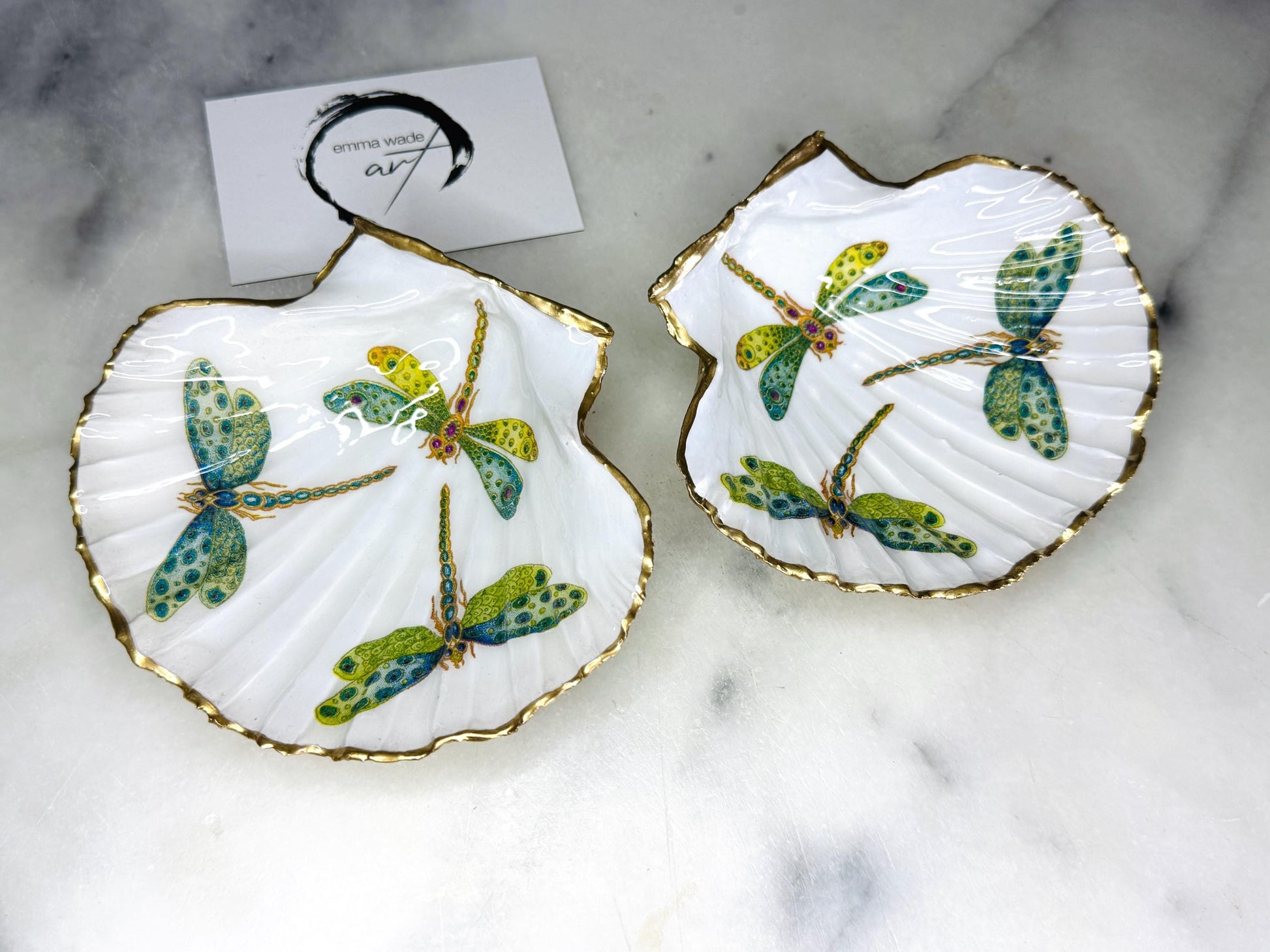 Handmade dragonfly scallop shell trinket dish with gold leaf edging and glossy resin finish. Coastal jewellery and ring dish crafted from a natural Dorset scallop shell, featuring colourful dragonfly artwork. Decorative shell bowl photographed on a light background, showing the natural shell shape and shimmering gilded edges, ideal for holding rings, earrings, trinkets or small treasures.
