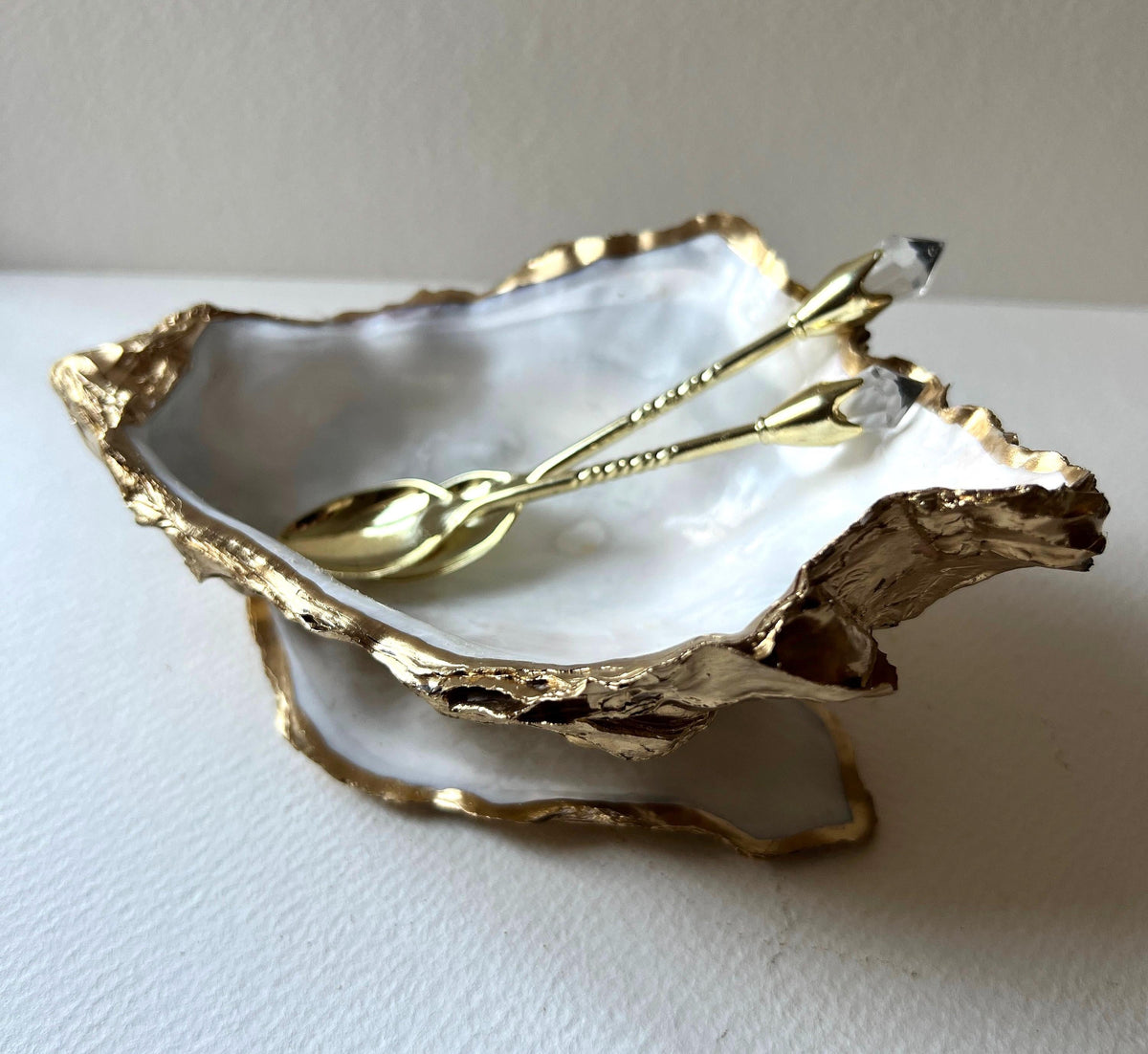 Extra large Dorset oyster shell serving dish set with natural pearl interior and hand-applied gold leaf edging, featuring a cupped XL oyster shell with matching flat shell base. Luxury coastal home décor ideal as a sugar dish, serving bowl, coffee station accessory, or elegant host gift. Handmade using sustainably sourced UK oyster shells and finished with glossy resin and optional gold serving accessories.