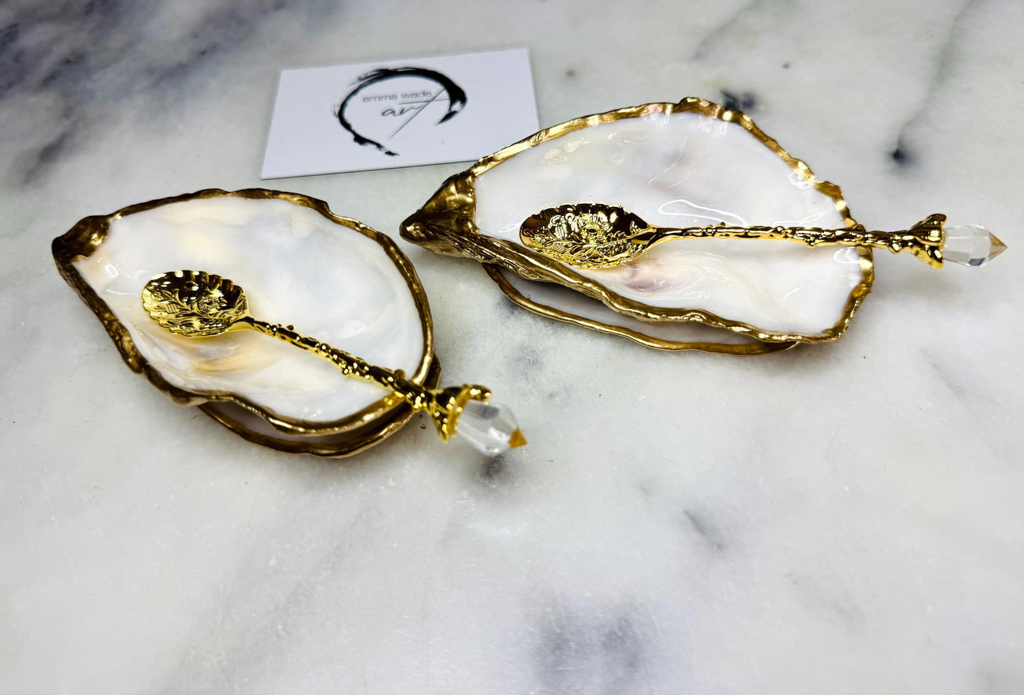 Handmade gold leaf oyster shell salt cellar set with pearl interiors and optional gold spoons. Coastal pinch pots made from natural Dorset oyster shells, sealed with food-safe glossy resin and finished with gilded edges. Luxury tableware set photographed on a light background, showing two shell salt dishes and matching spoons, ideal for serving salt, pepper or spices at dinner parties and stylish table settings.