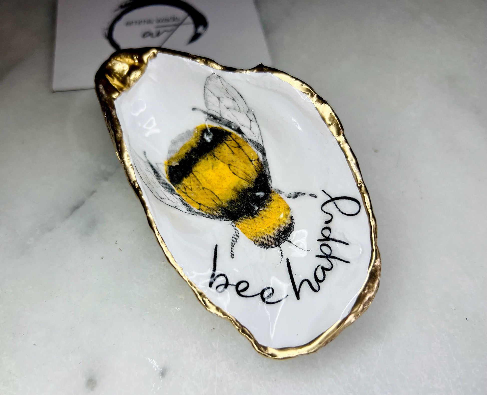 bee happy oyster shell trinket dish, Dorset oyster shell jewellery holder, handmade bee design coastal decor, gold leaf gilded oyster shell ornament, sustainable oyster shell dish UK, bumble bee oyster shell jewellery tray, nature inspired bee oyster shell gift, eco friendly oyster shell bathroom accessory, oyster shell salt and pepper pinch pot, unique bee themed oyster shell keepsake, handmade Dorset oyster shell decor, bee lover jewellery dish gift, coastal oyster shell art UK