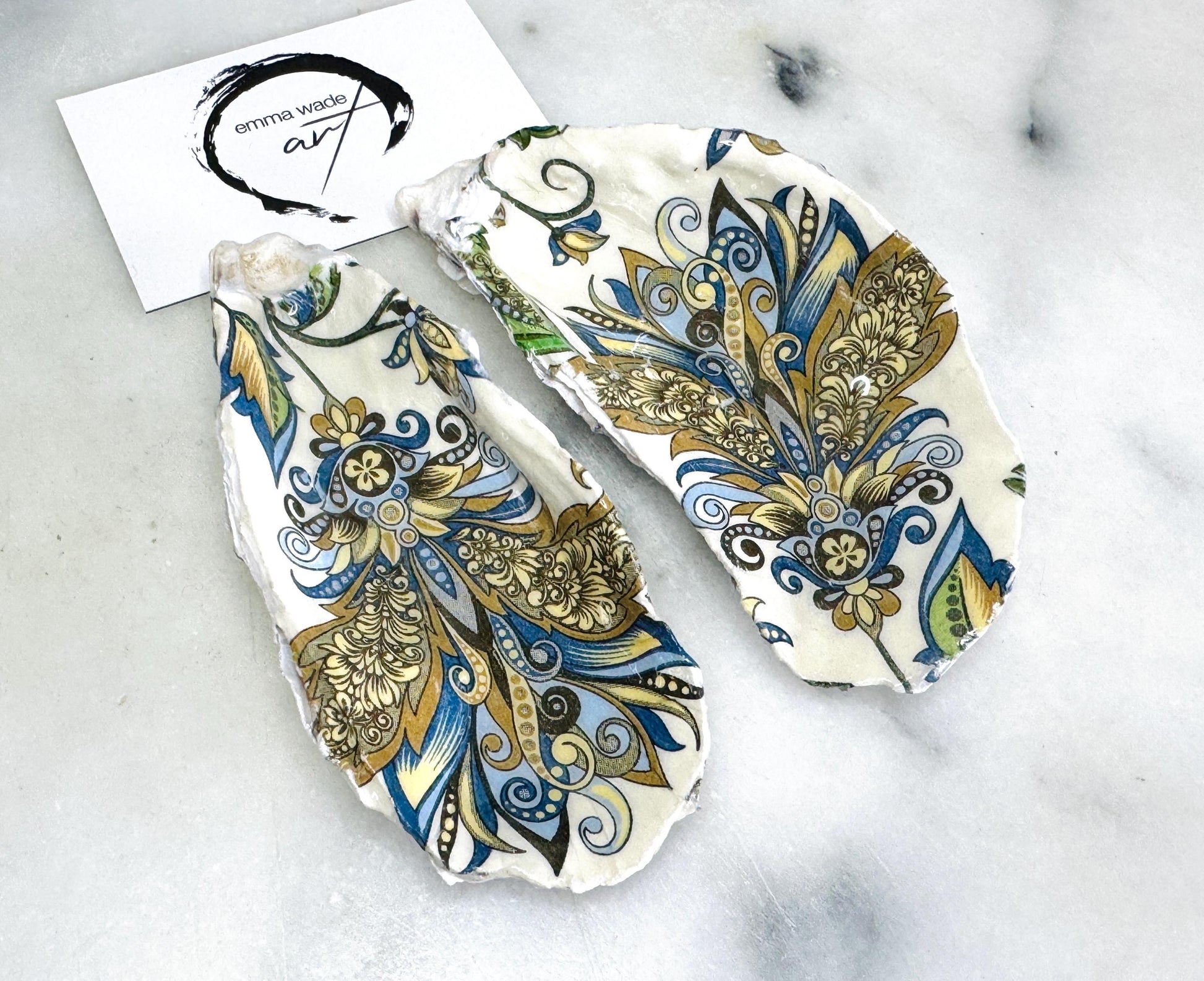 Handmade oyster shell salt and pepper dishes shown as a matching pair, decorated in a baroque gold design on natural Dorset shells, displayed on a light marble background as elegant coastal table decor and a unique hostess or wedding gift.