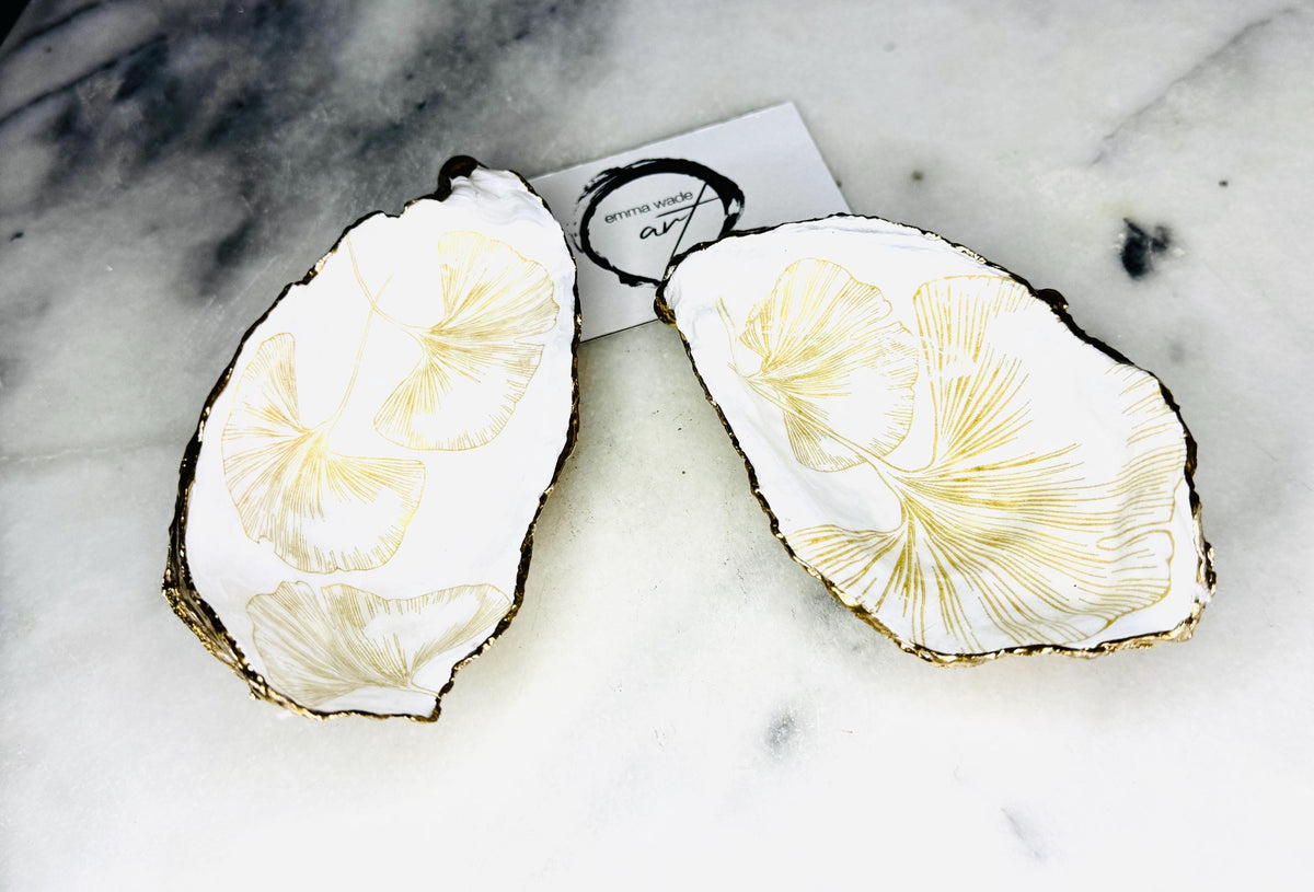 Pair of handmade Dorset oyster shell salt and pepper pinch pots featuring elegant Japanese Ginkgo floral artwork in soft gold and pearl tones with hand-applied gold leaf edging. Coastal luxury cruet set sealed in glossy Crystal resin with optional gold crystal spoons.