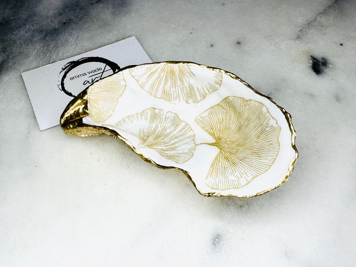 Pair of handmade Dorset oyster shell salt and pepper pinch pots featuring elegant Japanese Ginkgo floral artwork in soft gold and pearl tones with hand-applied gold leaf edging. Coastal luxury cruet set sealed in glossy Crystal resin with optional gold crystal spoons.