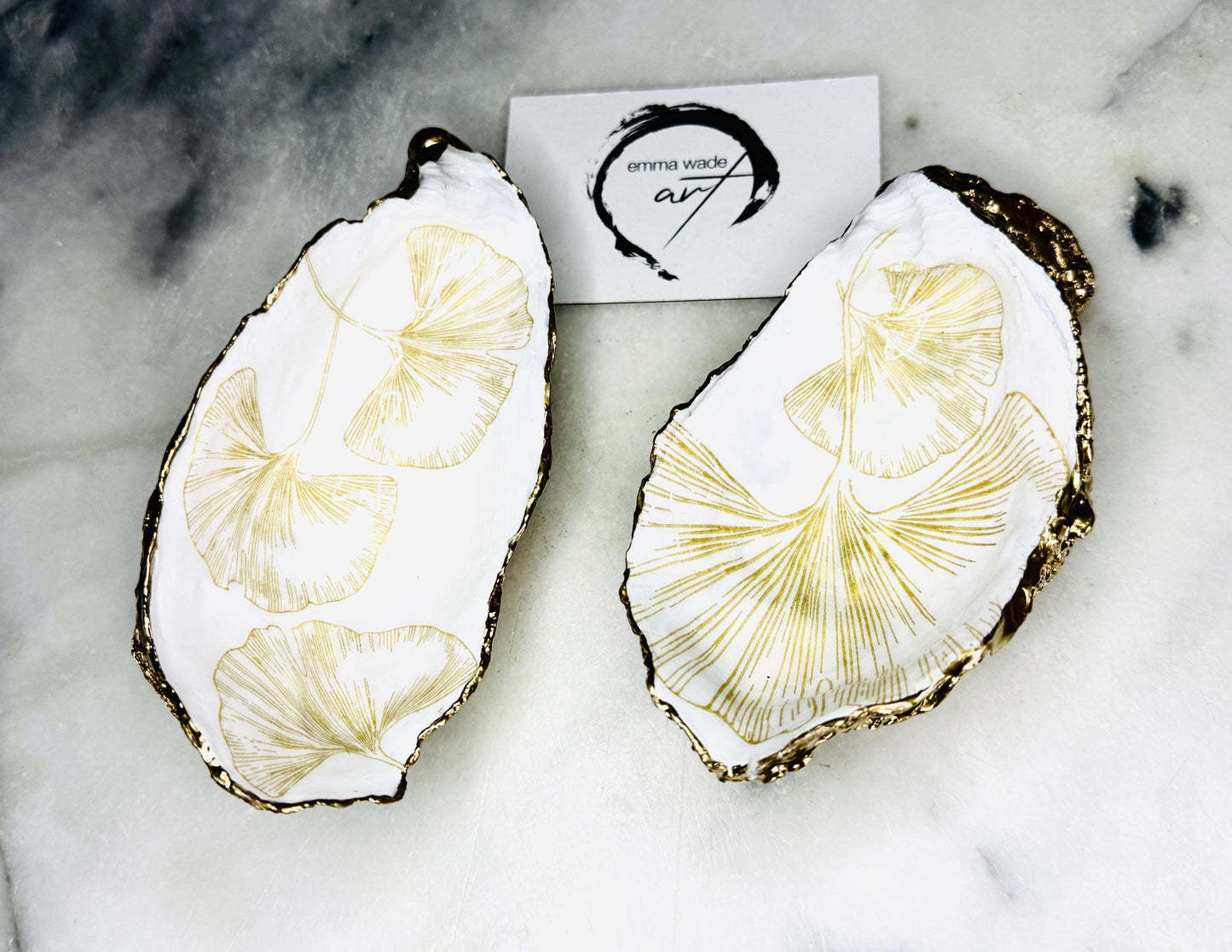 Pair of handmade Dorset oyster shell salt and pepper pinch pots featuring elegant Japanese Ginkgo floral artwork in soft gold and pearl tones with hand-applied gold leaf edging. Coastal luxury cruet set sealed in glossy Crystal resin with optional gold crystal spoons.