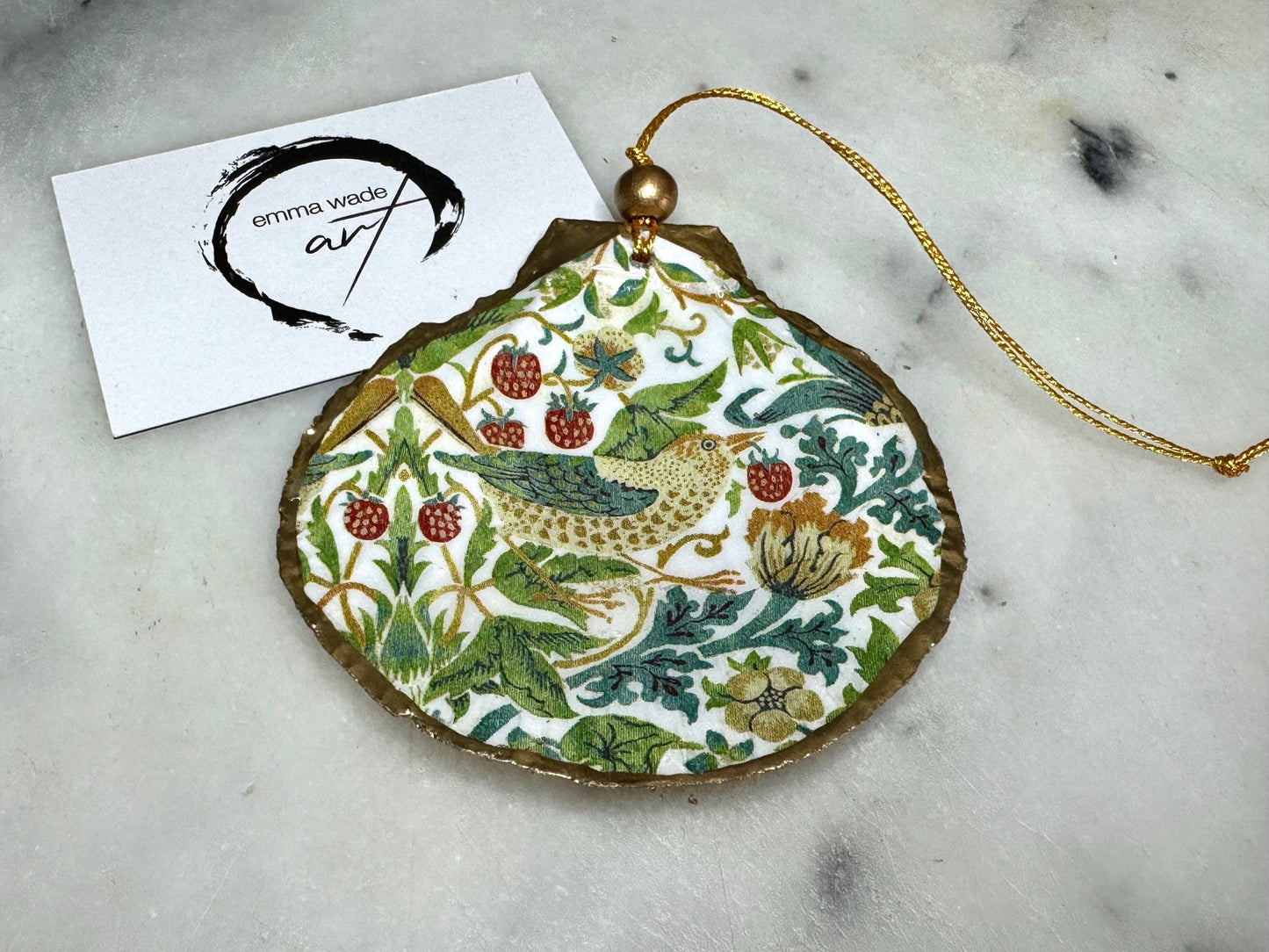 Handmade William Morris Strawberry Thief scallop shell hanging ornaments in four colourways with birds, floral patterns and gold leaf edging. Coastal shell ornaments finished in glossy resin with gold hanging cords for Christmas trees or year-round home decor. UK Heritage Gift