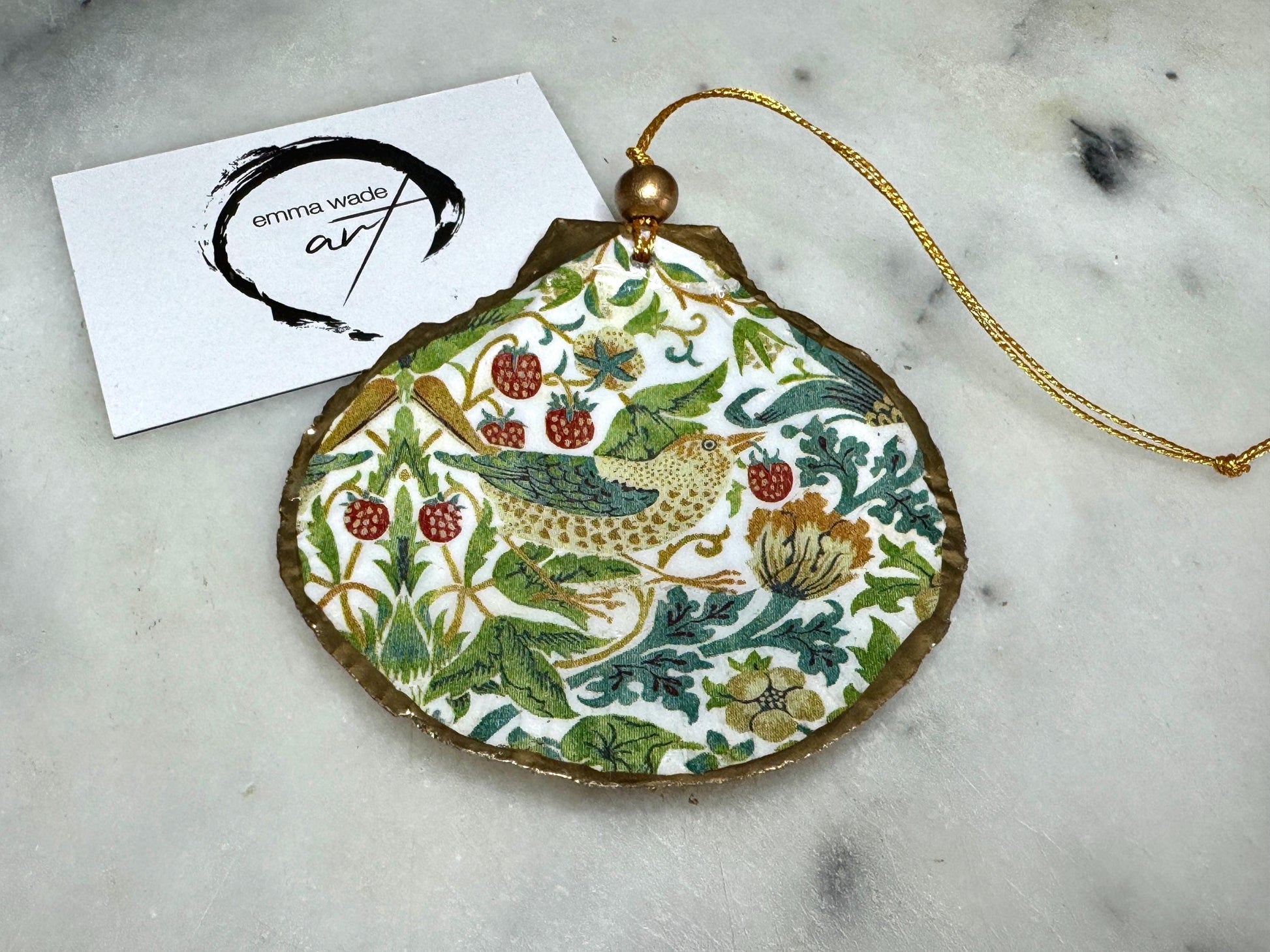 Handmade William Morris Strawberry Thief scallop shell hanging ornaments in four colourways with birds, floral patterns and gold leaf edging. Coastal shell ornaments finished in glossy resin with gold hanging cords for Christmas trees or year-round home decor. UK Heritage Gift