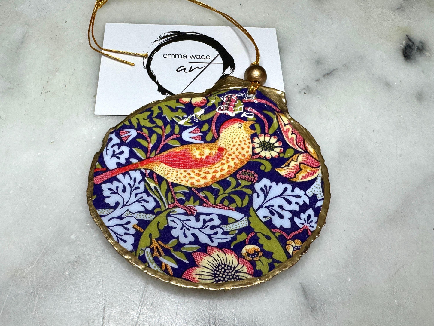 Handmade William Morris Strawberry Thief scallop shell hanging ornaments in four colourways with birds, floral patterns and gold leaf edging. Coastal shell ornaments finished in glossy resin with gold hanging cords for Christmas trees or year-round home decor. UK Heritage Gift