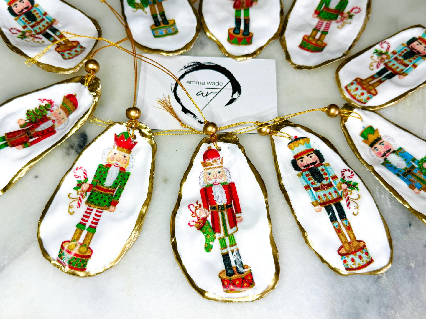 Handmade Nutcracker oyster shell Christmas ornaments with gold gilded edges and glossy resin finish. Traditional festive Nutcracker designs on natural pearl Dorset oyster shells in red, green, aqua, blue and gold tones, styled as luxury coastal Christmas tree decorations.