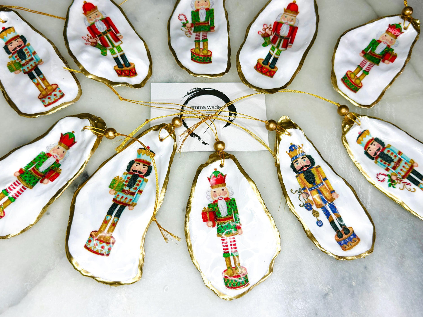 Handmade Nutcracker oyster shell Christmas ornaments with gold gilded edges and glossy resin finish. Traditional festive Nutcracker designs on natural pearl Dorset oyster shells in red, green, aqua, blue and gold tones, styled as luxury coastal Christmas tree decorations.