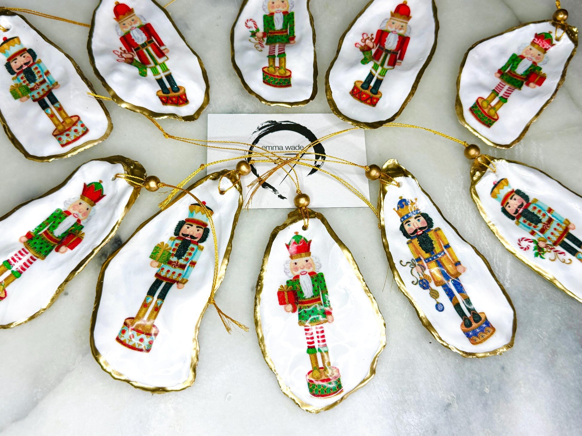 Handmade Nutcracker oyster shell Christmas ornaments with gold gilded edges and glossy resin finish. Traditional festive Nutcracker designs on natural pearl Dorset oyster shells in red, green, aqua, blue and gold tones, styled as luxury coastal Christmas tree decorations.