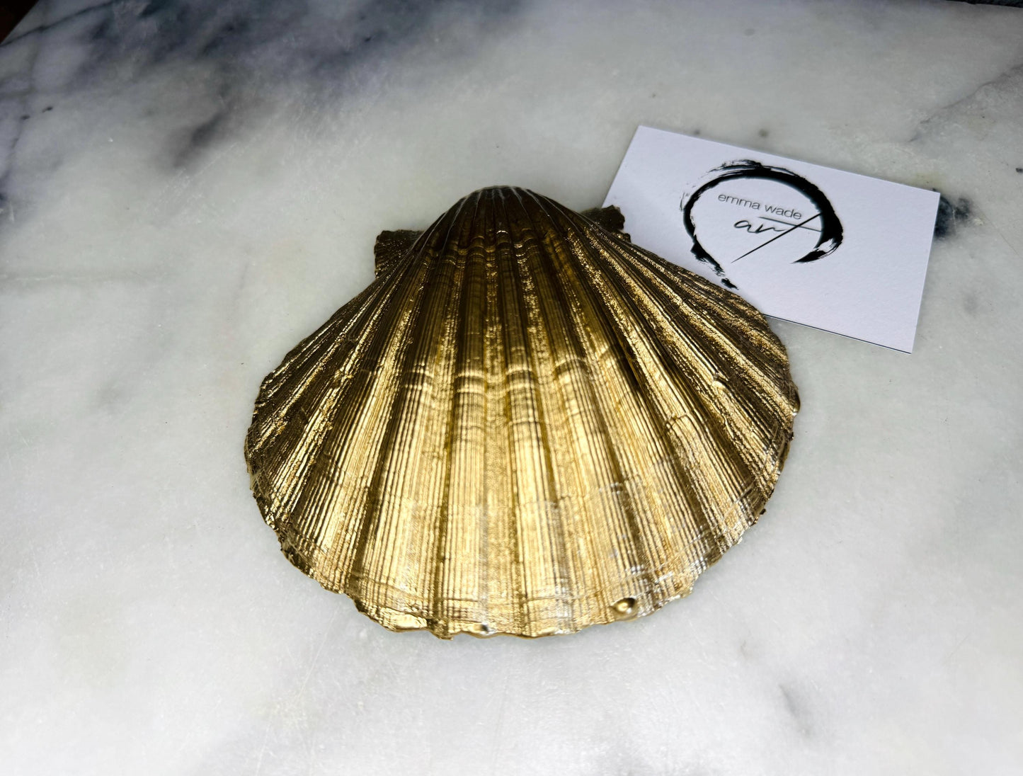 Handmade block print scallop shell trinket dish featuring a blue leaf pattern, finished with gilded gold leaf edges and sealed with a glossy resin. Crafted from a natural Dorset scallop shell, shown as a decorative jewellery tray on a light background, perfect for rings, earrings and small keepsakes. Coastal-inspired home decor, ideal for a bedside table, dressing table or bathroom, each piece one of a kind.