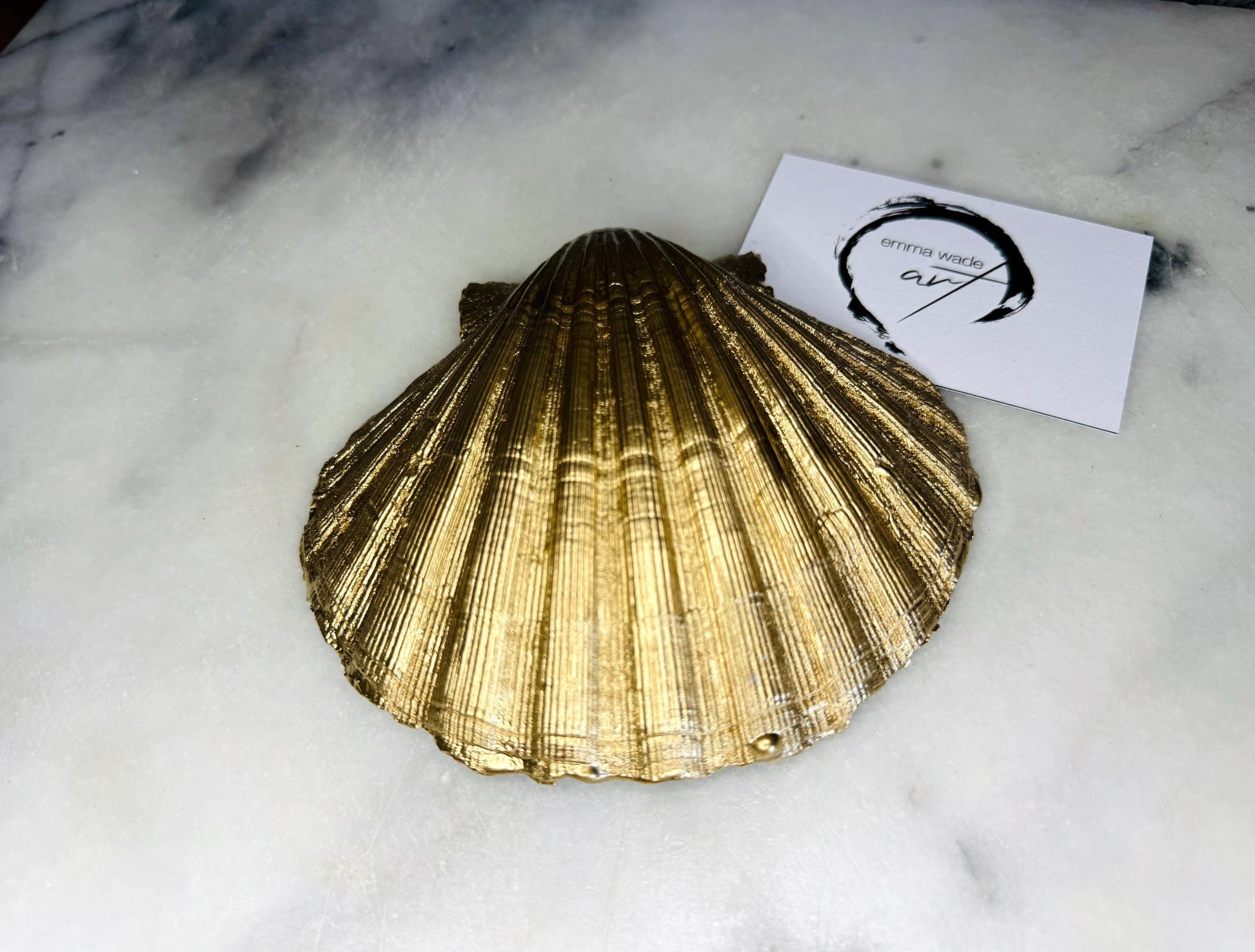 Handmade block print scallop shell trinket dish featuring a blue leaf pattern, finished with gilded gold leaf edges and sealed with a glossy resin. Crafted from a natural Dorset scallop shell, shown as a decorative jewellery tray on a light background, perfect for rings, earrings and small keepsakes. Coastal-inspired home decor, ideal for a bedside table, dressing table or bathroom, each piece one of a kind.