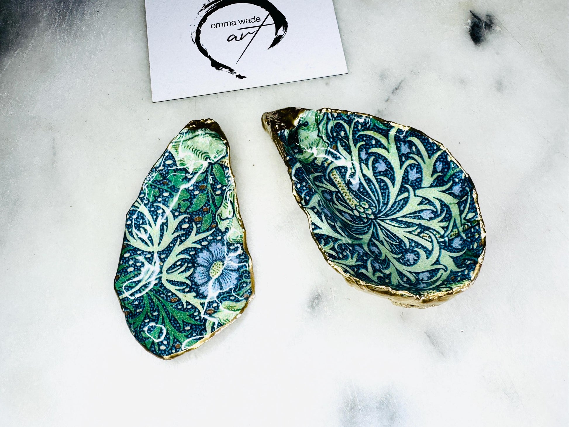 William Morris Seaweed design decoupage oyster shell ring dish with gold leaf exterior and glossy resin finish, shown on a light background. Natural Dorset oyster shell jewellery dish used as a ring holder, featuring a green and blue patterned interior, polished edges, and handcrafted coastal keepsake style. Ideal as an engagement ring dish, wedding ring holder, or jewellery trinket dish.
