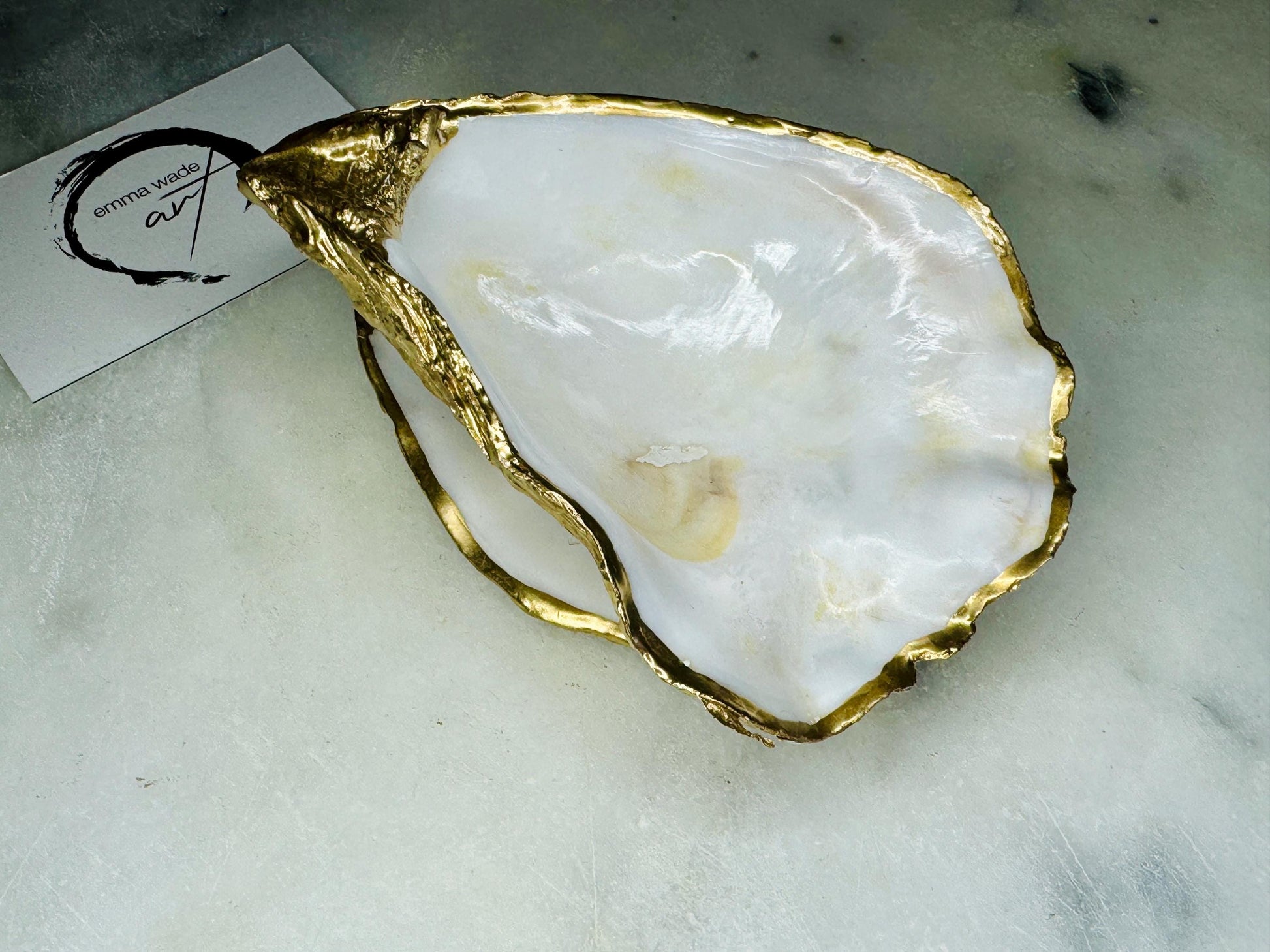 Natural pearl finish Dorset oyster shell ring box with gold leaf rim and polished interior, photographed open on a light background. Handcrafted oyster shell jewellery box showing the smooth pearl interior, organic shell shape, and gilded edges, designed to hold engagement rings, wedding rings, or small jewellery pieces.