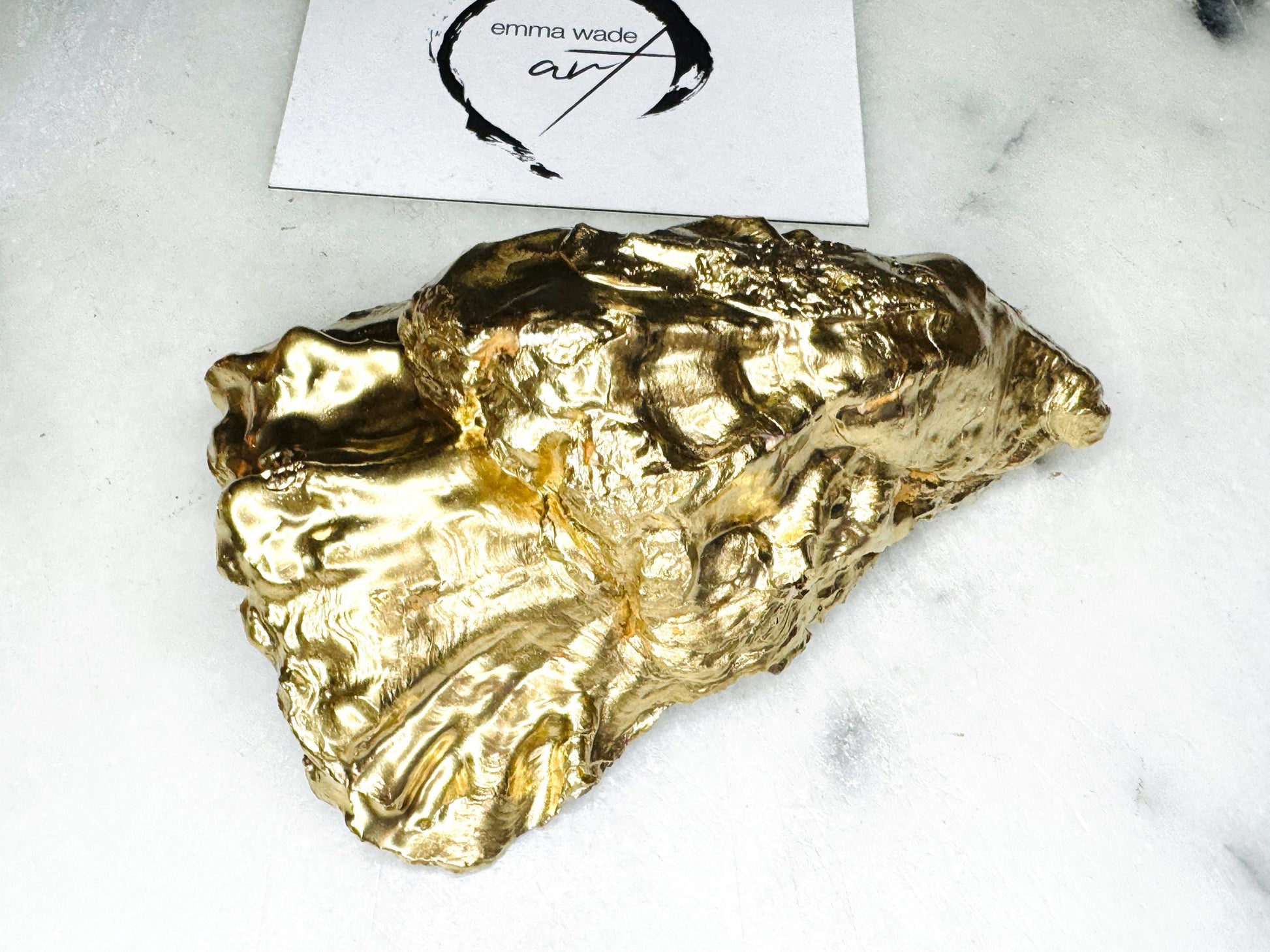 Handmade Dorset oyster shell trinket dish with blue porcelain-style bird design, gold leaf gilded edges and glossy resin finish. Coastal jewellery holder and ring dish photographed on a light surface, showing the natural shell shape and pearly interior. Unique sustainably sourced shell, sold individually as decorative coastal home décor or a thoughtful gift.