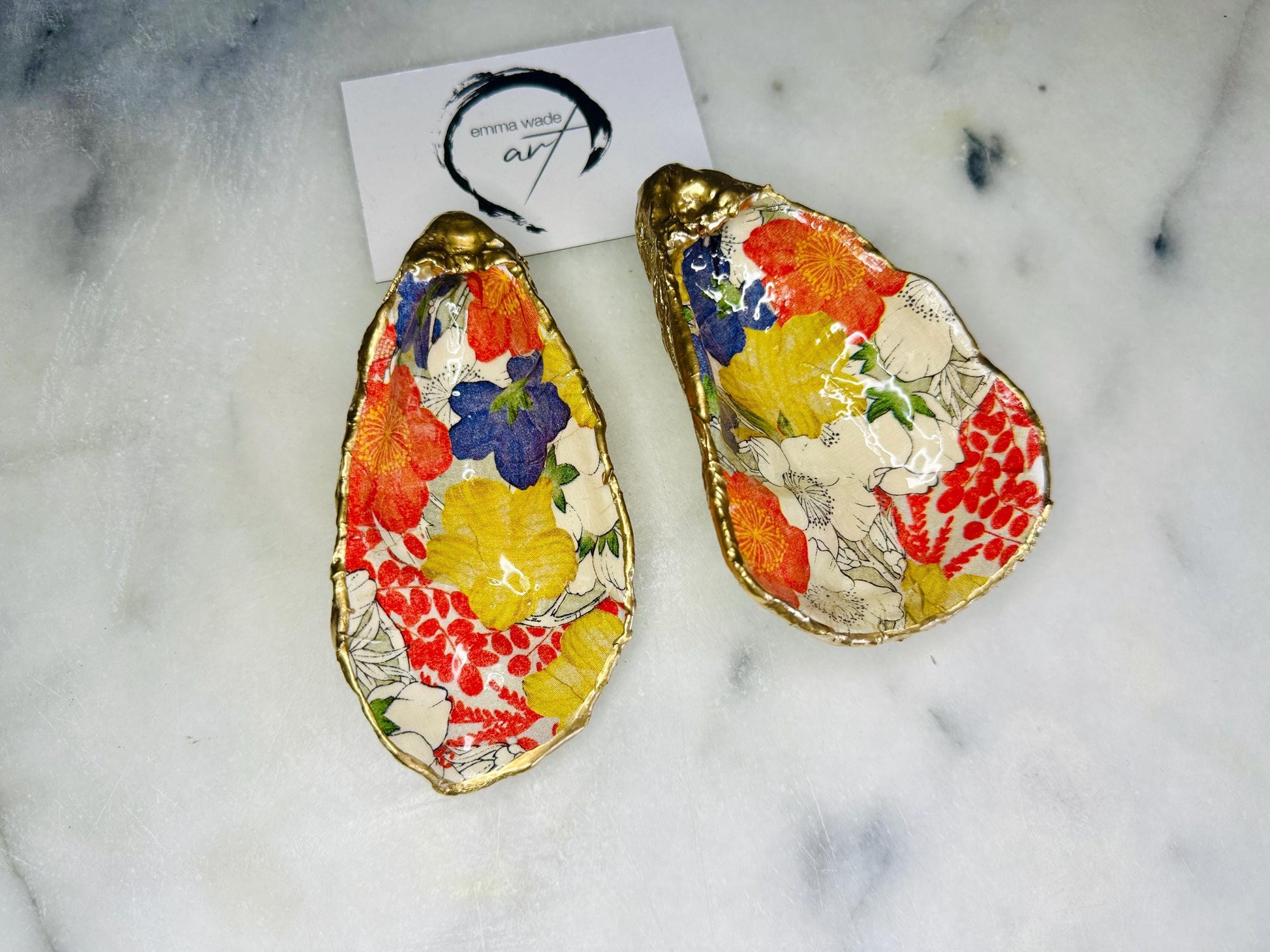 Handmade oyster shell trinket dish featuring a colourful Japanese kimono-style floral design applied with decoupage, finished with hand-gilded gold leaf edges and sealed in glossy clear resin. Natural Dorset oyster shell used as a jewellery dish or ring holder, photographed on a light surface, showcasing the vibrant flowers and luxury gold detailing. Ideal as coastal home decor or a unique handmade gift.