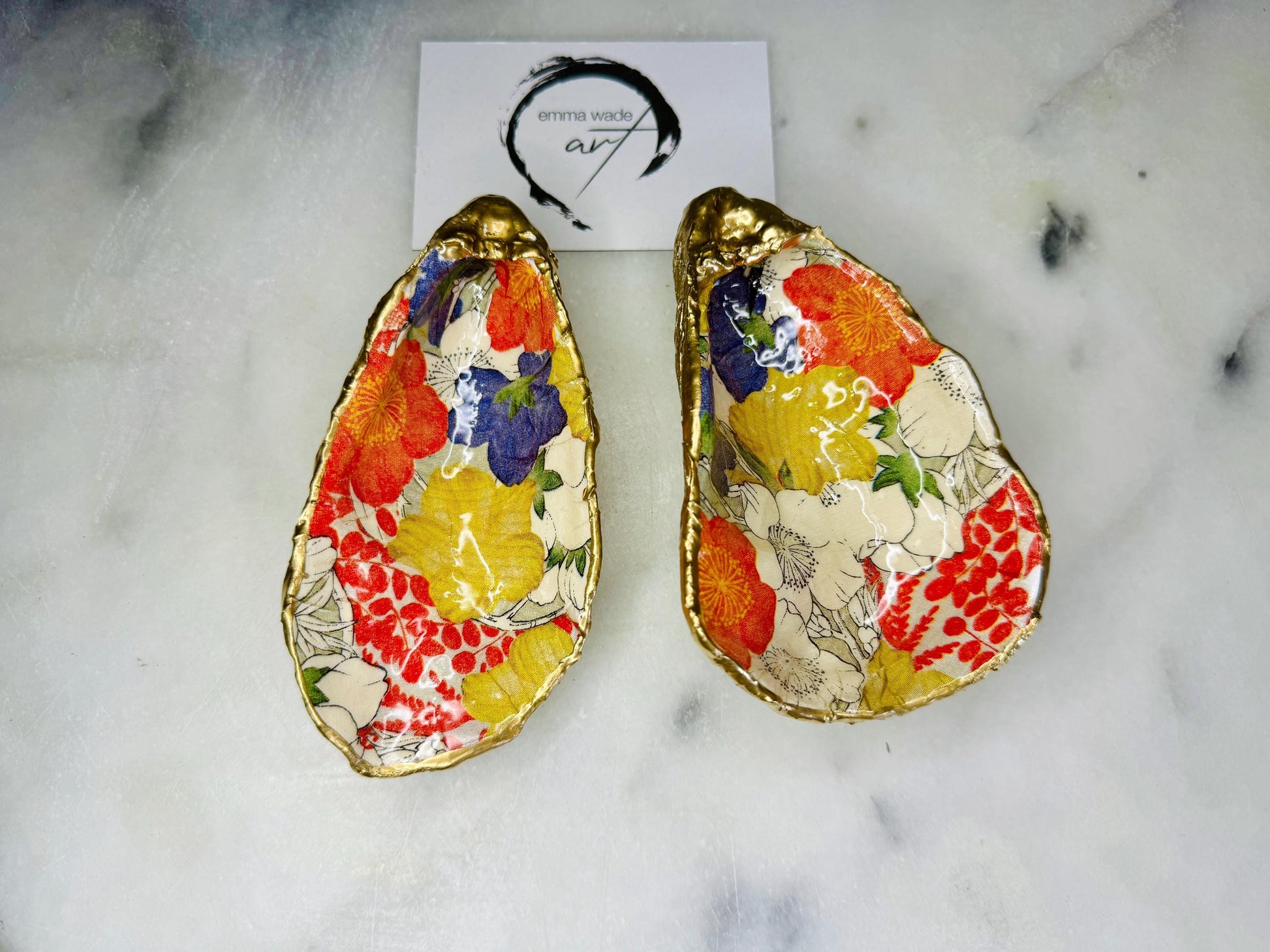 Handmade oyster shell trinket dish featuring a colourful Japanese kimono-style floral design applied with decoupage, finished with hand-gilded gold leaf edges and sealed in glossy clear resin. Natural Dorset oyster shell used as a jewellery dish or ring holder, photographed on a light surface, showcasing the vibrant flowers and luxury gold detailing. Ideal as coastal home decor or a unique handmade gift.