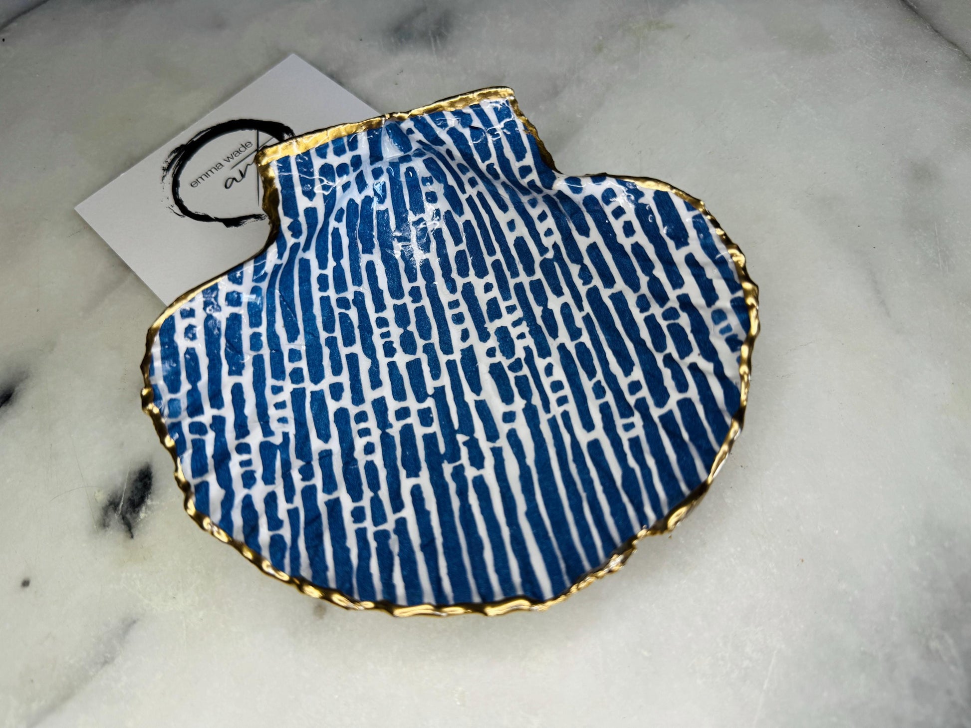 Handmade blue and white scallop shell trinket dish with gold leaf edging, crafted from a genuine Dorset shell and sealed with glossy resin. Coastal ring dish and jewellery holder featuring elegant blue line design, displayed in gift packaging. Artisan shell decor handmade in Surrey, perfect for coastal home styling, wedding gifts or nautical themed interiors.