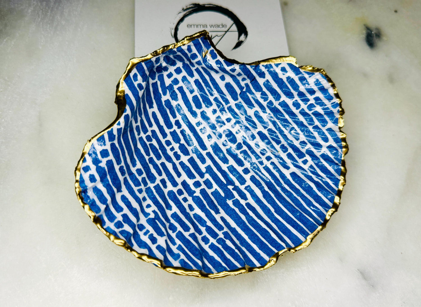Handmade blue and white scallop shell trinket dish with gold leaf edging, crafted from a genuine Dorset shell and sealed with glossy resin. Coastal ring dish and jewellery holder featuring elegant blue line design, displayed in gift packaging. Artisan shell decor handmade in Surrey, perfect for coastal home styling, wedding gifts or nautical themed interiors.