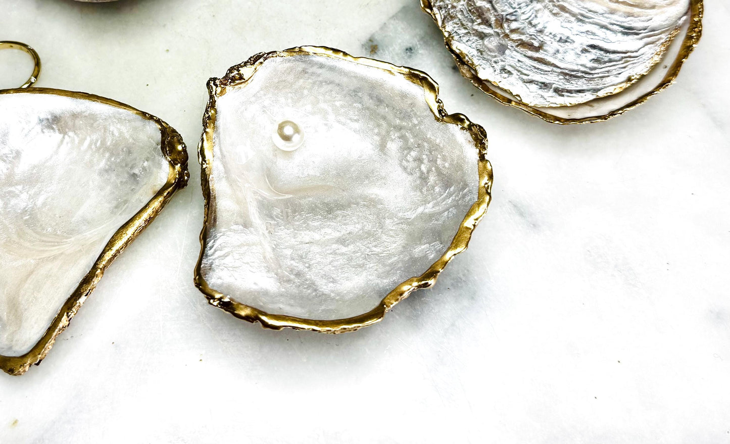 Natural saddle oyster shell ring box handcrafted with pearlised interior and exterior, sealed with high gloss resin and edged in liquid gold leaf, optional Swarovski pearl ring holder, elegant coastal wedding ring bearer box or proposal ring dish styled on neutral background