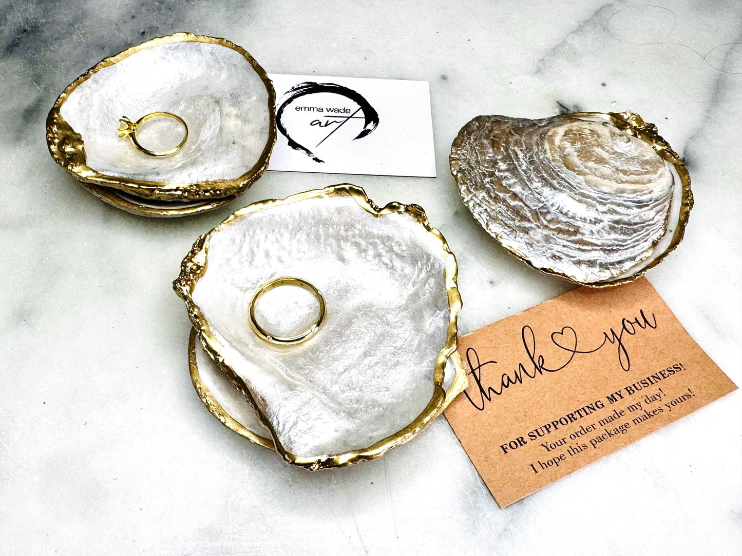 Handmade saddle oyster shell ring box with pearlescent interior and pearlised exterior, finished with gold leaf gilded edges and optional Swarovski pearl ring holder, luxury coastal wedding ring bearer box, proposal ring presentation dish, artisan shell jewellery holder styled on neutral marble background