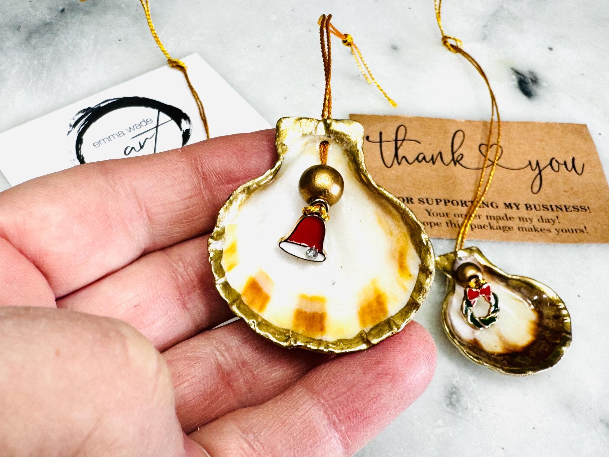 Handmade scallop shell Christmas ornaments with gold leaf edging and enamel charms, natural pearl shell decorations, Dorset shell baubles, festive tree decorations, stocking filler gifts, coastal Christmas decor, small hanging ornaments with gold string, unique handmade shell keepsake, wreath sleigh tree reindeer bell penguin charms, luxury Christmas gift idea