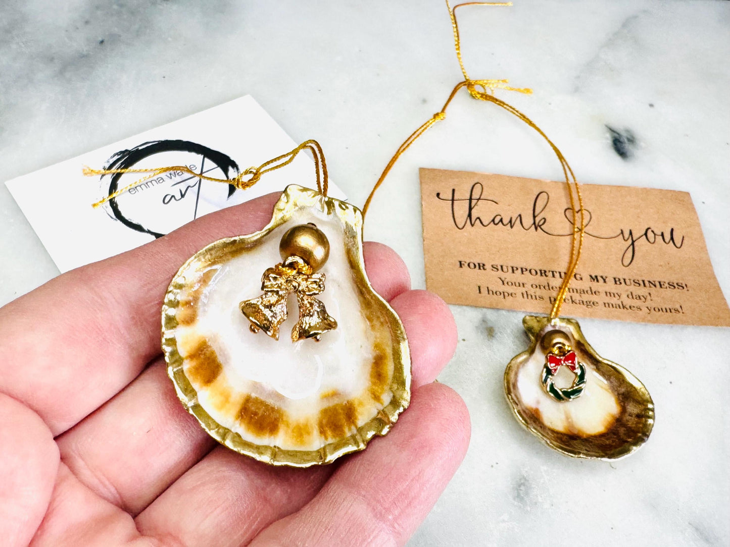 Handmade scallop shell Christmas ornaments with gold leaf edging and enamel charms, natural pearl shell decorations, Dorset shell baubles, festive tree decorations, stocking filler gifts, coastal Christmas decor, small hanging ornaments with gold string, unique handmade shell keepsake, wreath sleigh tree reindeer bell penguin charms, luxury Christmas gift idea