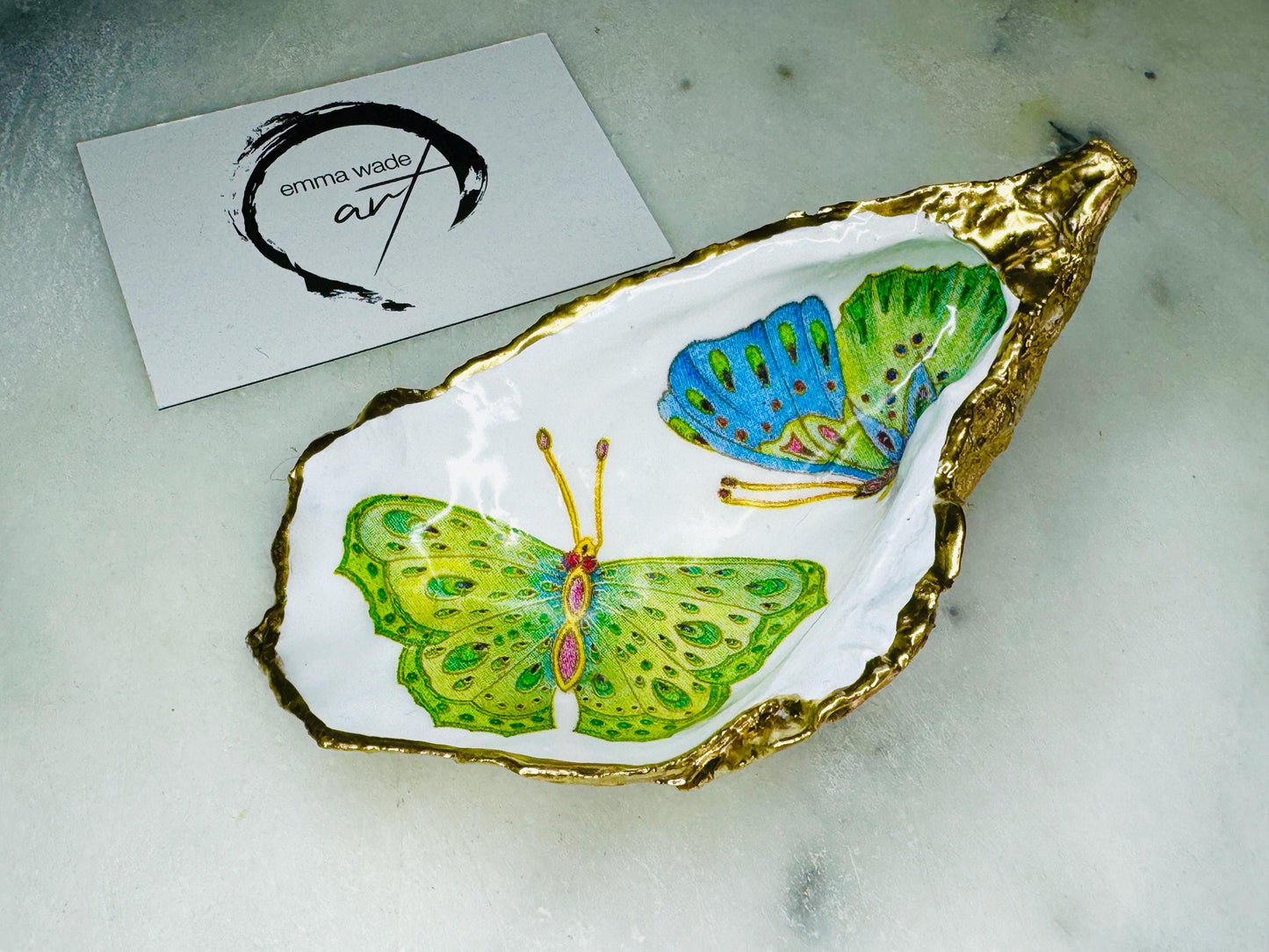 Handmade butterfly oyster shell trinket dish with colourful blue green and pink butterfly designs, edged and backed in gold leaf, Dorset coastal shell jewellery holder with glossy resin finish, luxury ring dish, coastal home decor gift, unique handmade shell dish for jewellery storage, beach house accessory, UK artisan oyster shell dish