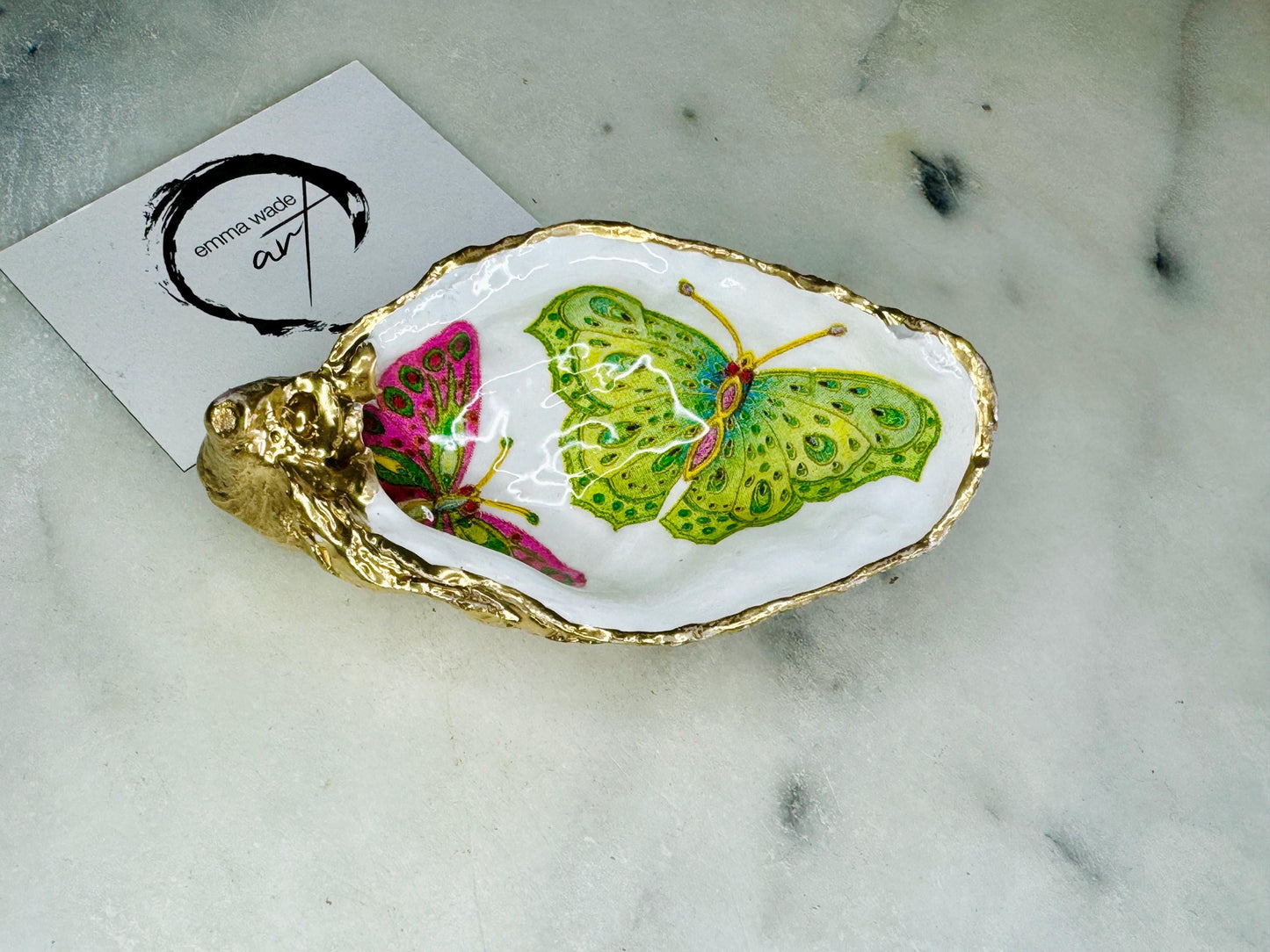 Handmade butterfly oyster shell trinket dish with colourful blue green and pink butterfly designs, edged and backed in gold leaf, Dorset coastal shell jewellery holder with glossy resin finish, luxury ring dish, coastal home decor gift, unique handmade shell dish for jewellery storage, beach house accessory, UK artisan oyster shell dish