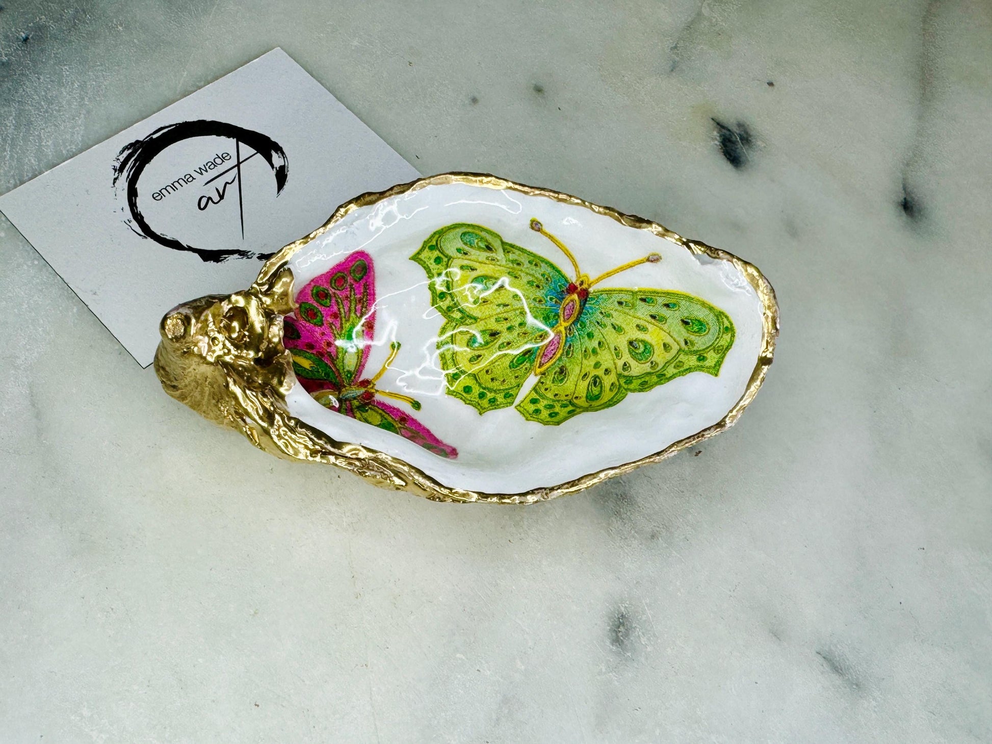 Handmade butterfly oyster shell trinket dish with colourful blue green and pink butterfly designs, edged and backed in gold leaf, Dorset coastal shell jewellery holder with glossy resin finish, luxury ring dish, coastal home decor gift, unique handmade shell dish for jewellery storage, beach house accessory, UK artisan oyster shell dish