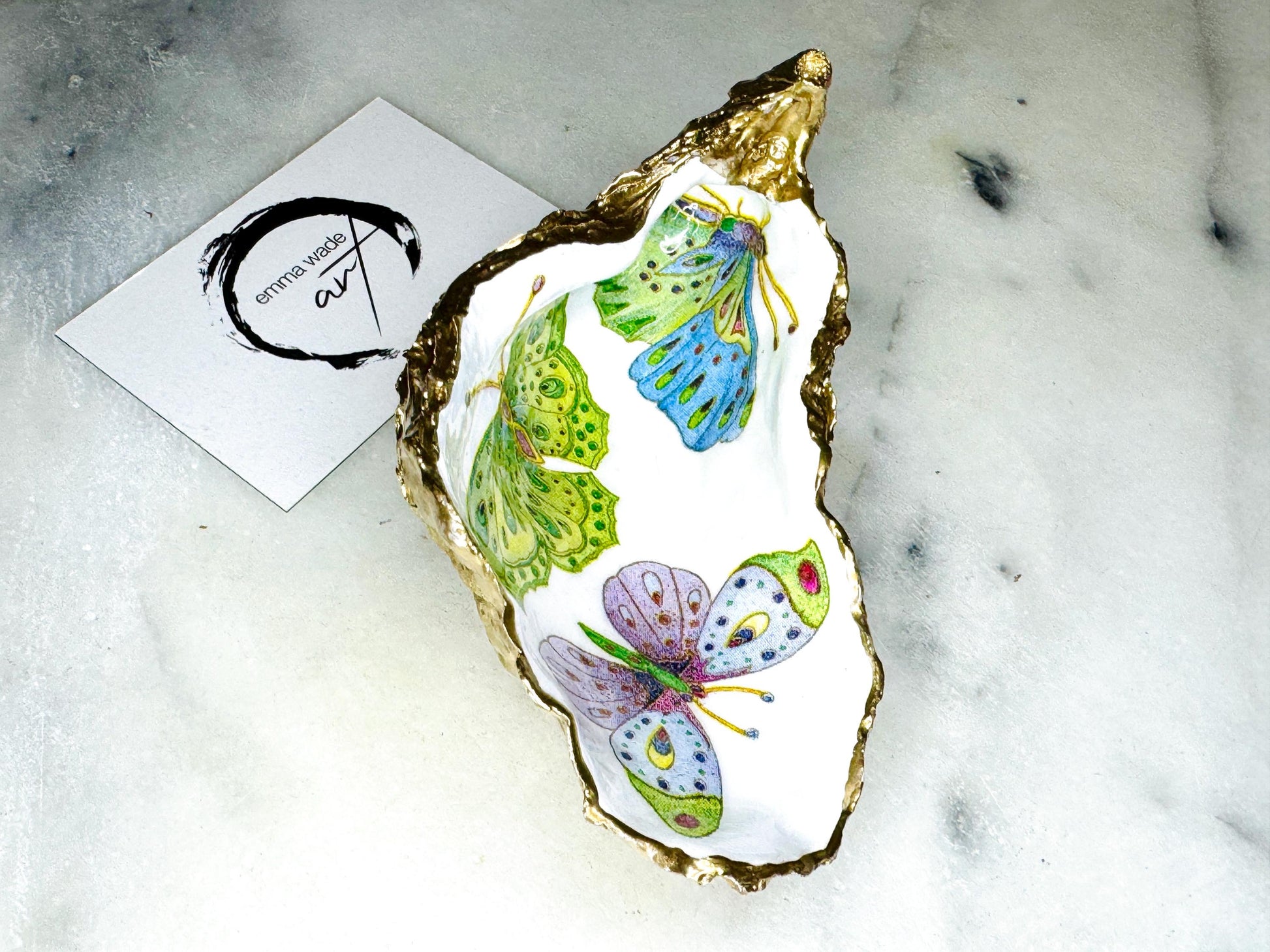 Handmade butterfly oyster shell trinket dish with colourful blue green and pink butterfly designs, edged and backed in gold leaf, Dorset coastal shell jewellery holder with glossy resin finish, luxury ring dish, coastal home decor gift, unique handmade shell dish for jewellery storage, beach house accessory, UK artisan oyster shell dish