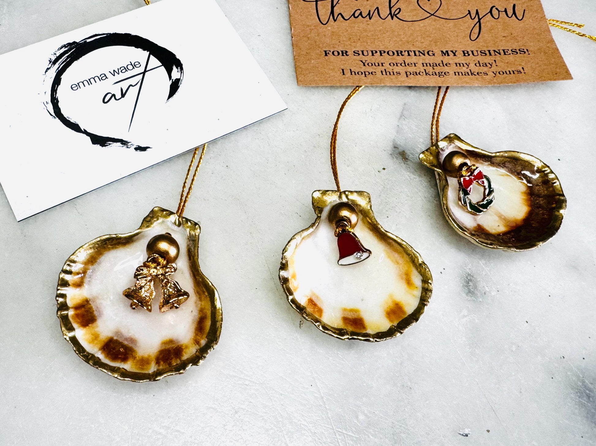 Handmade scallop shell Christmas ornaments with gold leaf edging and enamel charms, natural pearl shell decorations, Dorset shell baubles, festive tree decorations, stocking filler gifts, coastal Christmas decor, small hanging ornaments with gold string, unique handmade shell keepsake, wreath sleigh tree reindeer bell penguin charms, luxury Christmas gift idea