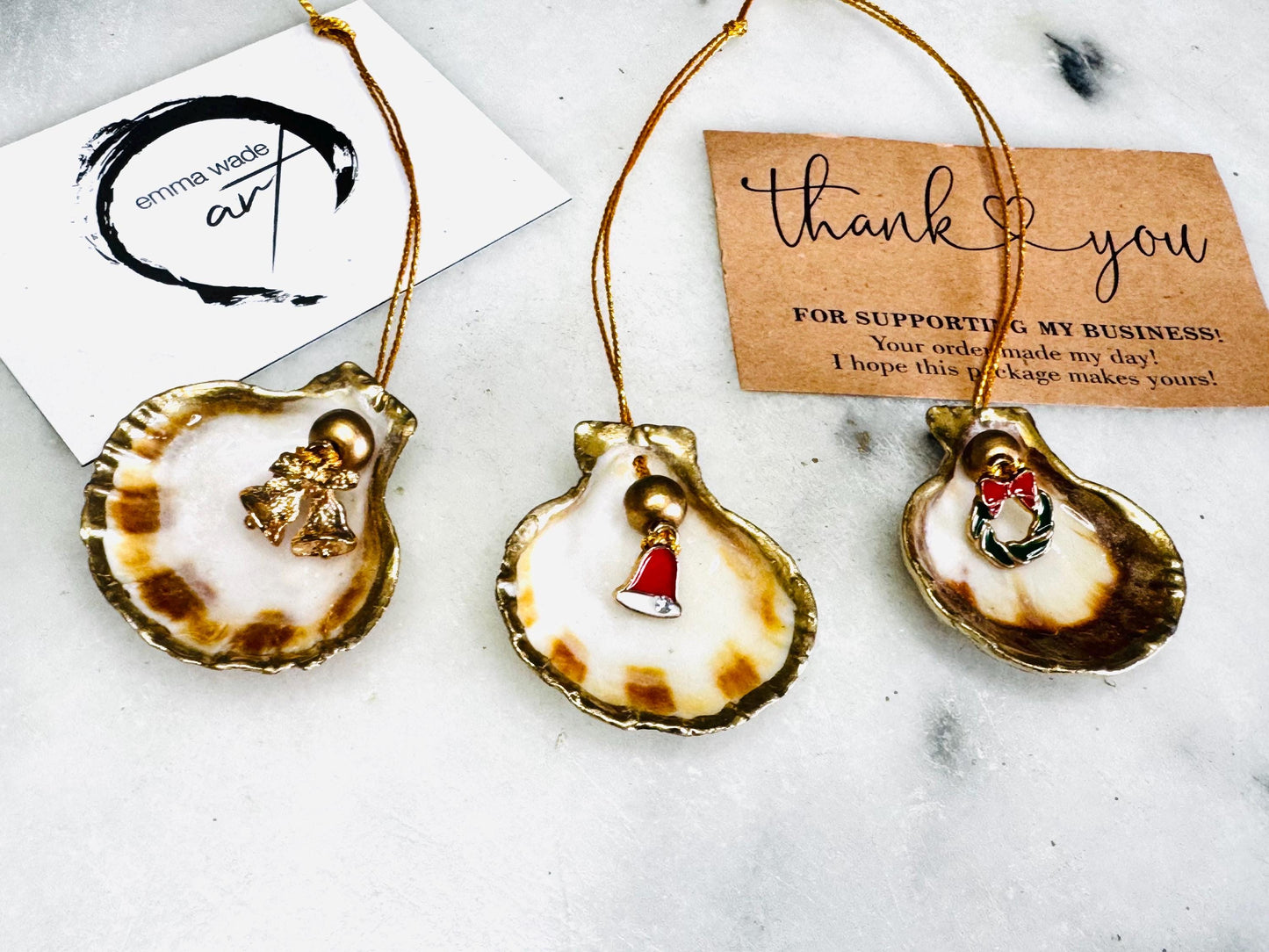Handmade scallop shell Christmas ornaments with gold leaf edging and enamel charms, natural pearl shell decorations, Dorset shell baubles, festive tree decorations, stocking filler gifts, coastal Christmas decor, small hanging ornaments with gold string, unique handmade shell keepsake, wreath sleigh tree reindeer bell penguin charms, luxury Christmas gift idea