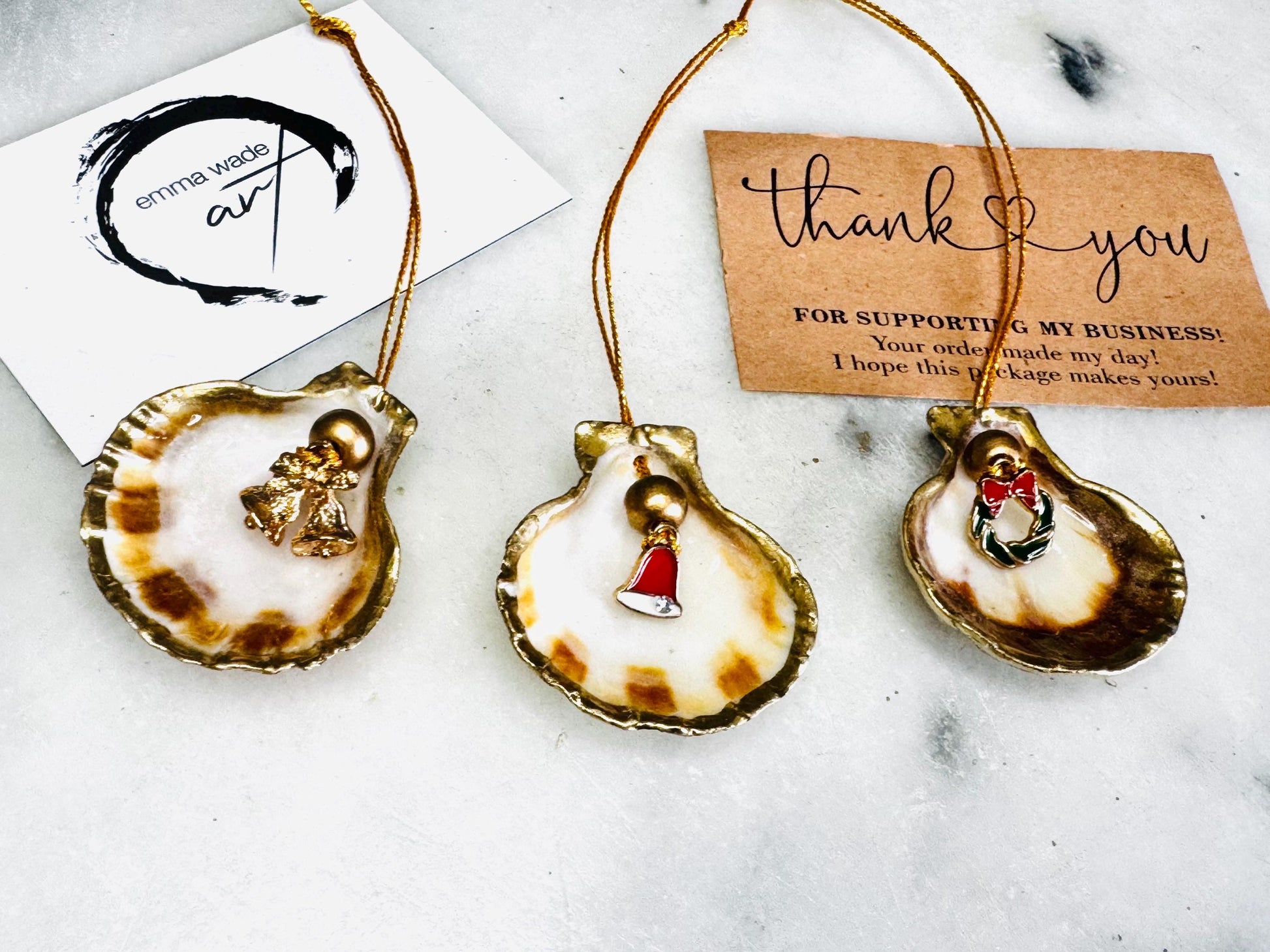 Handmade scallop shell Christmas ornaments with gold leaf edging and enamel charms, natural pearl shell decorations, Dorset shell baubles, festive tree decorations, stocking filler gifts, coastal Christmas decor, small hanging ornaments with gold string, unique handmade shell keepsake, wreath sleigh tree reindeer bell penguin charms, luxury Christmas gift idea