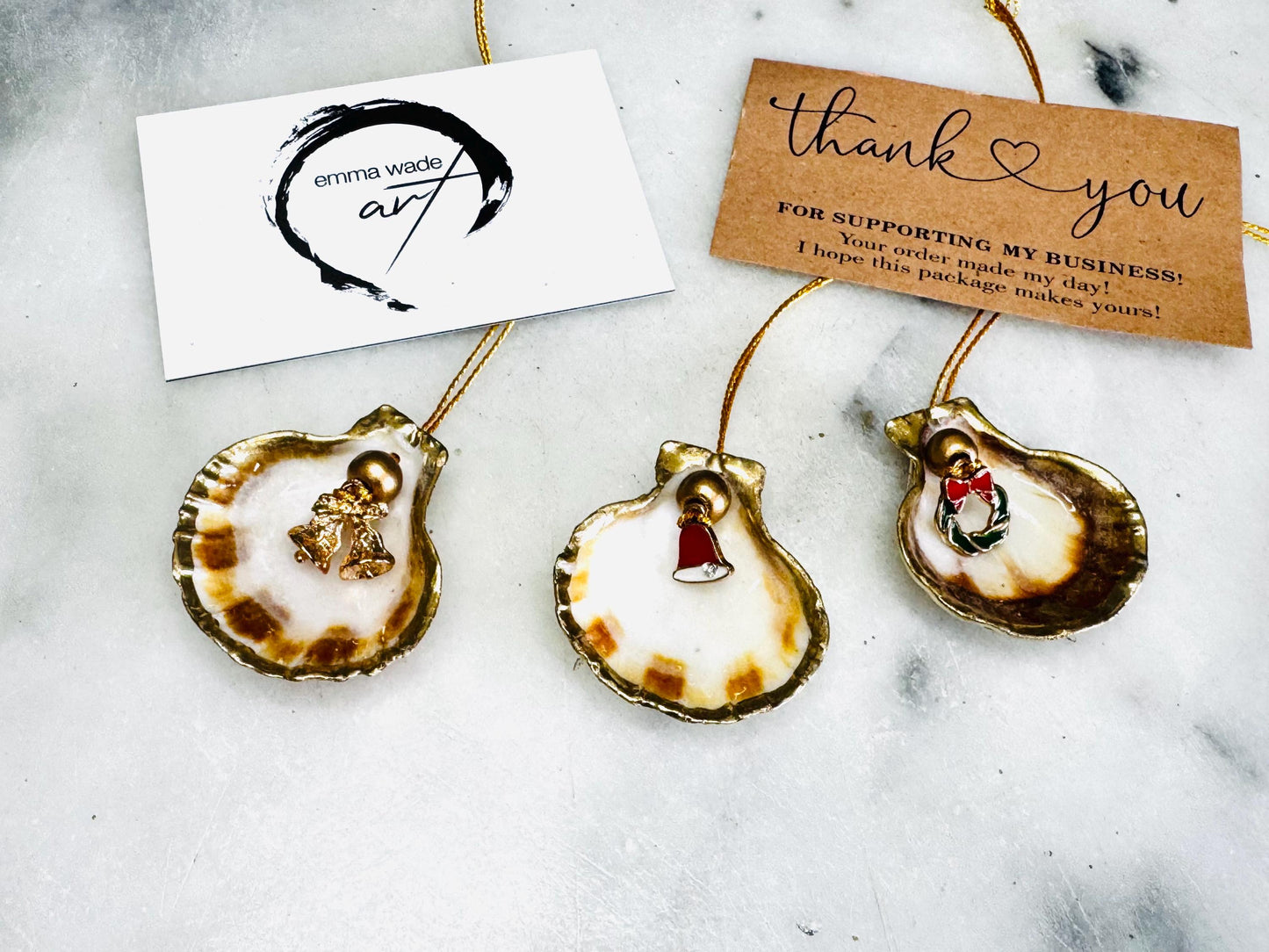 Handmade scallop shell Christmas ornaments with gold leaf edging and enamel charms, natural pearl shell decorations, Dorset shell baubles, festive tree decorations, stocking filler gifts, coastal Christmas decor, small hanging ornaments with gold string, unique handmade shell keepsake, wreath sleigh tree reindeer bell penguin charms, luxury Christmas gift idea