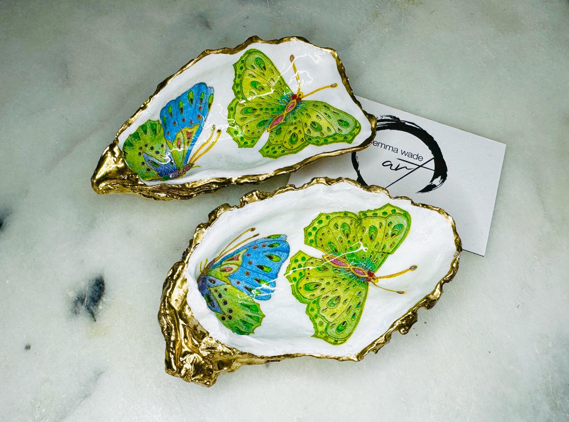 Handmade butterfly oyster shell trinket dish with colourful blue green and pink butterfly designs, edged and backed in gold leaf, Dorset coastal shell jewellery holder with glossy resin finish, luxury ring dish, coastal home decor gift, unique handmade shell dish for jewellery storage, beach house accessory, UK artisan oyster shell dish